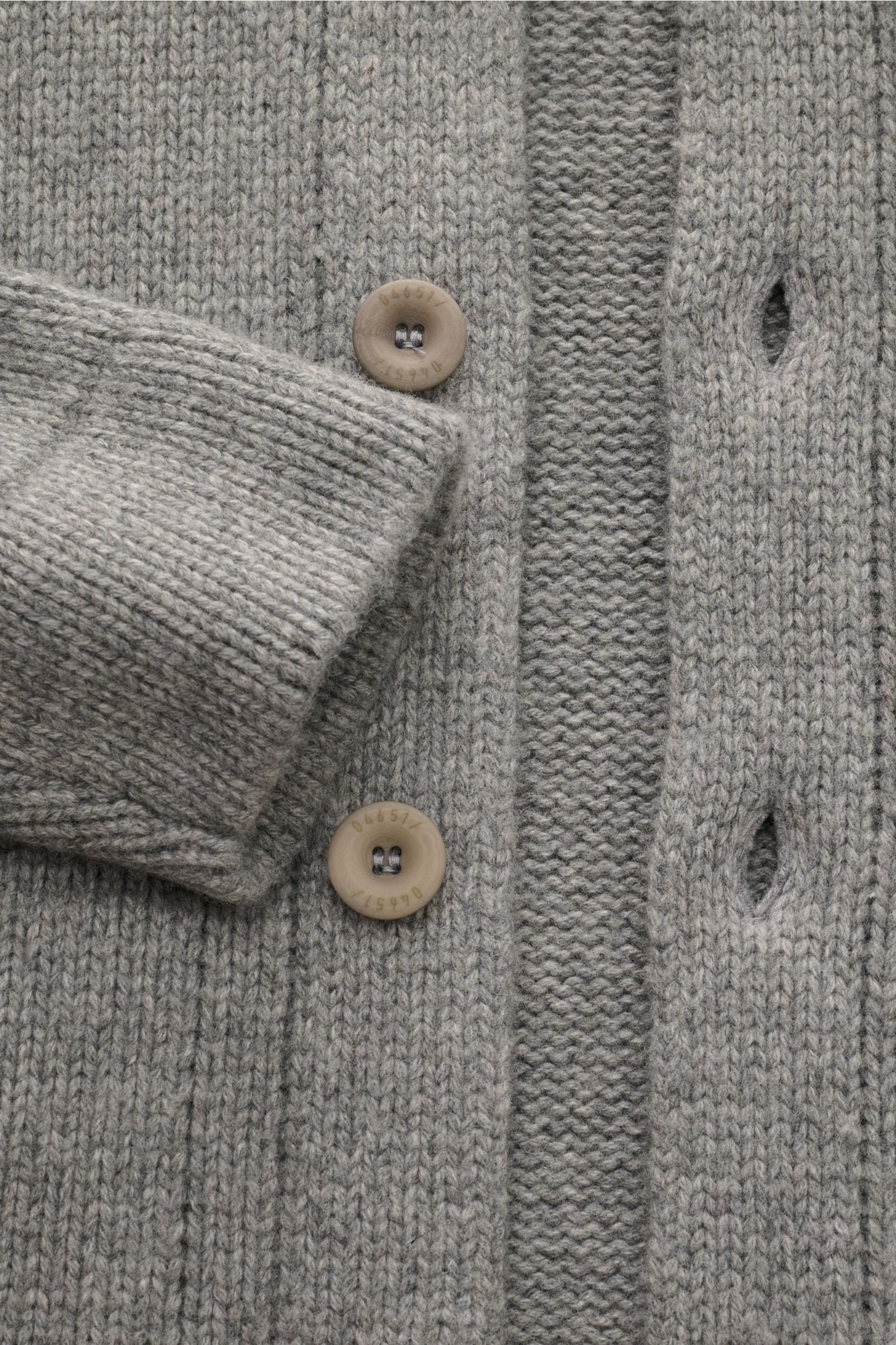 Nahaufnahme des 04651/ A trip in a bag Cardigan 'Boiled Blouson' grau meliert mit mittelfeinem Strick, sechs Knöpfen und Rippbündchen aus Woll-Mix.