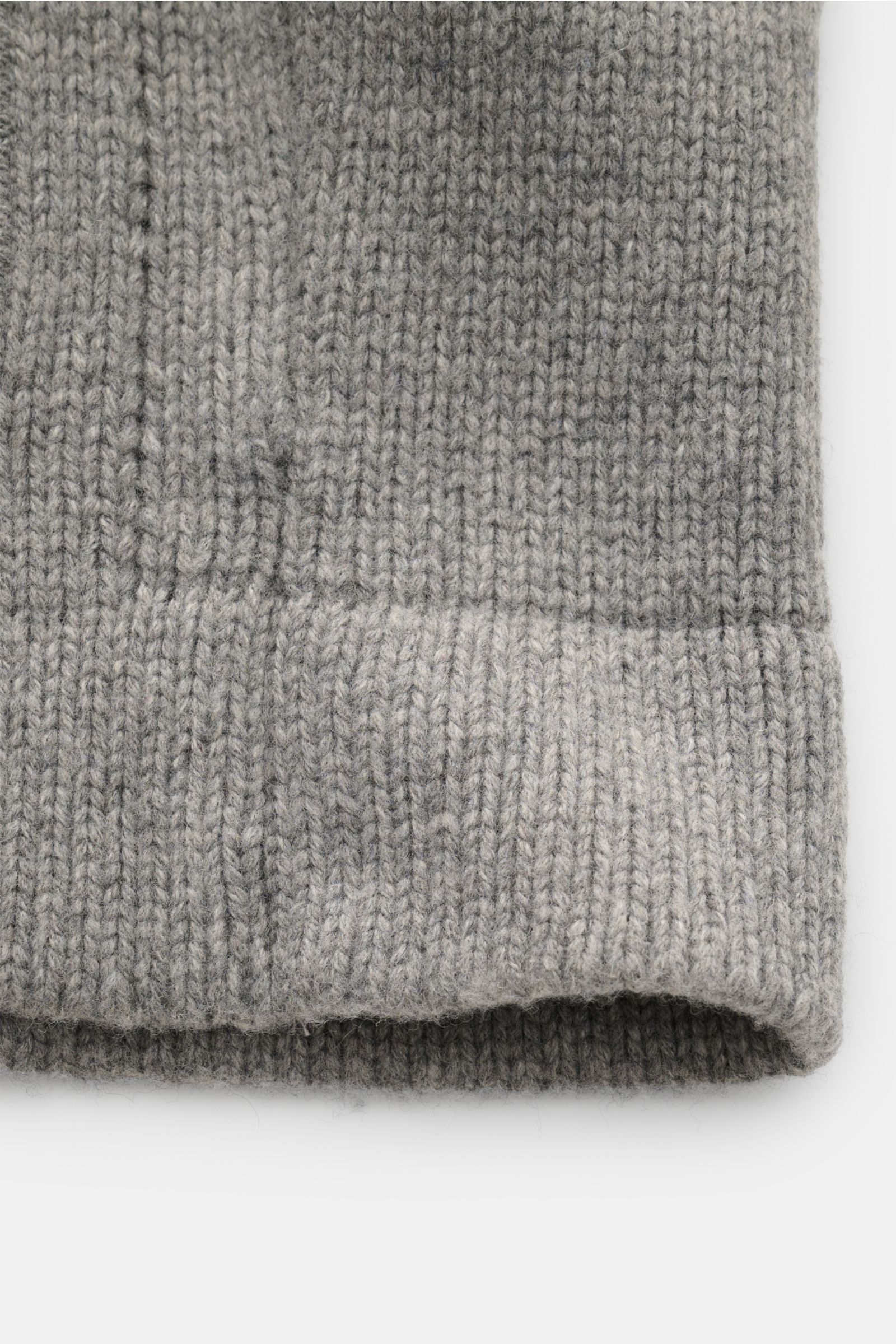 Graue Nahaufnahme des Rippbündchens vom 04651/ A trip in a bag Cardigan 'Boiled Blouson' mit mittelfeinem Strick aus Wollmix, Slim Fit, sechs Knöpfen und schräge Hüfttaschen, fotografiert aus frontaler Perspektive.