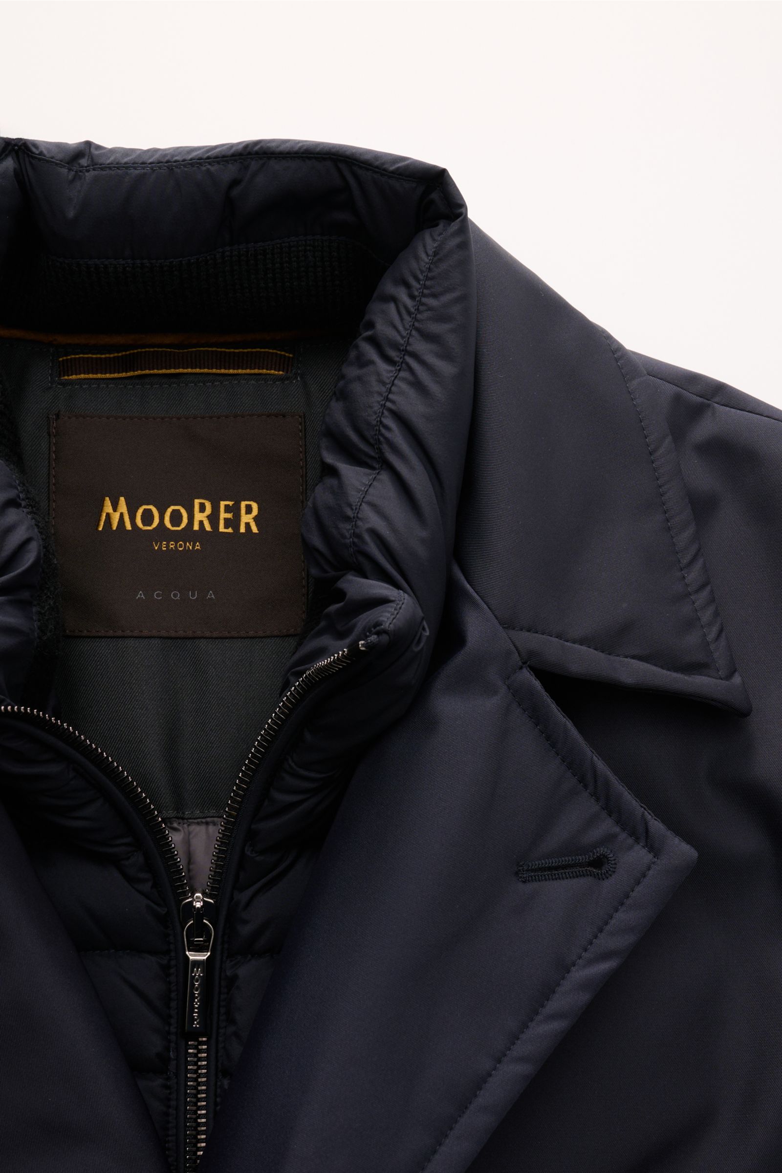 Close-up front view of Moorer Daunenjacke 'Bolgi' navy, showcasing its smooth gabardine fabric, padded collar, and zipper with label.

The description you provided:  
Eleganz trifft Funktion: Gefertigt aus edlem Gabardine mit seidig schimmernder Oberfl