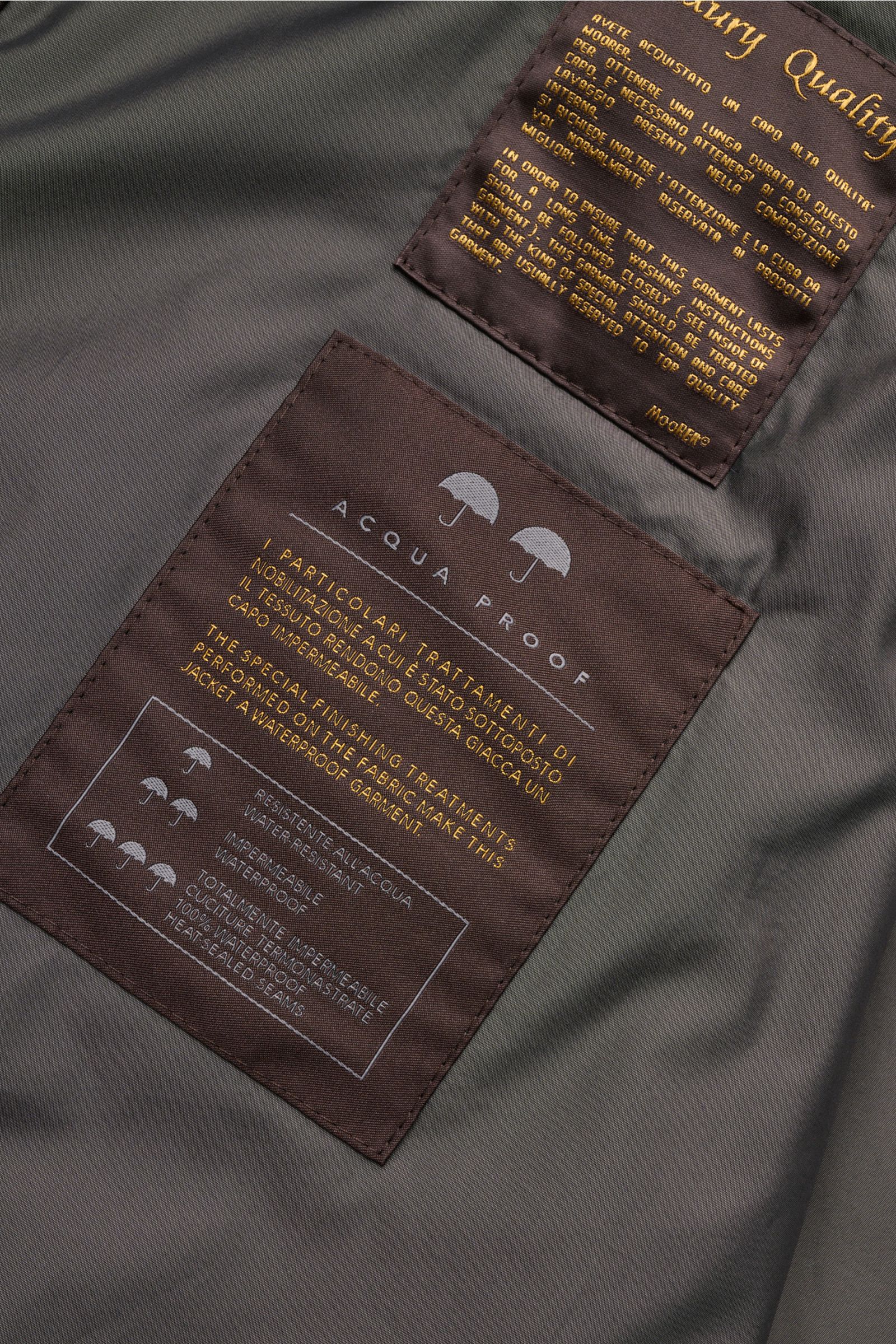 Close-up view of the interior labels of the Moorer Jacke 'Elson' navy, showing waterproof fabric and care instructions on dark fabric patches.