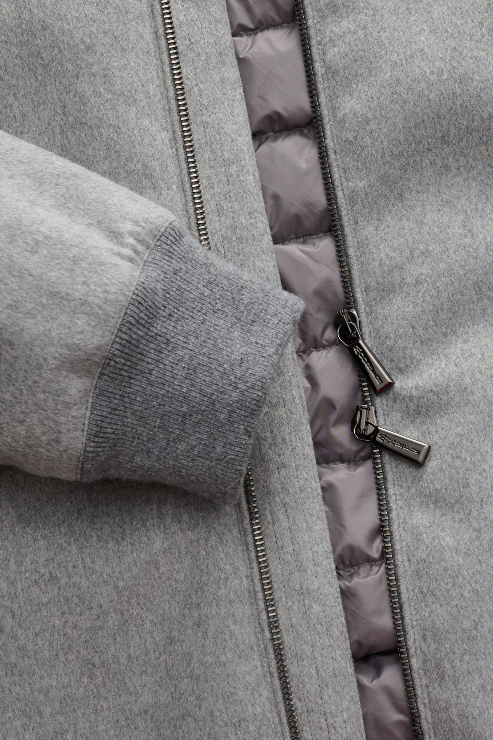 Nahaufnahme des Moorer Daunenblouson 'Oniro' grau von schräg oben, zeigt Slim Fit, Woll-Mix, Daunenfüllung, wasserabweisend, Reißverschluss und elastisches Ärmelbündchen.