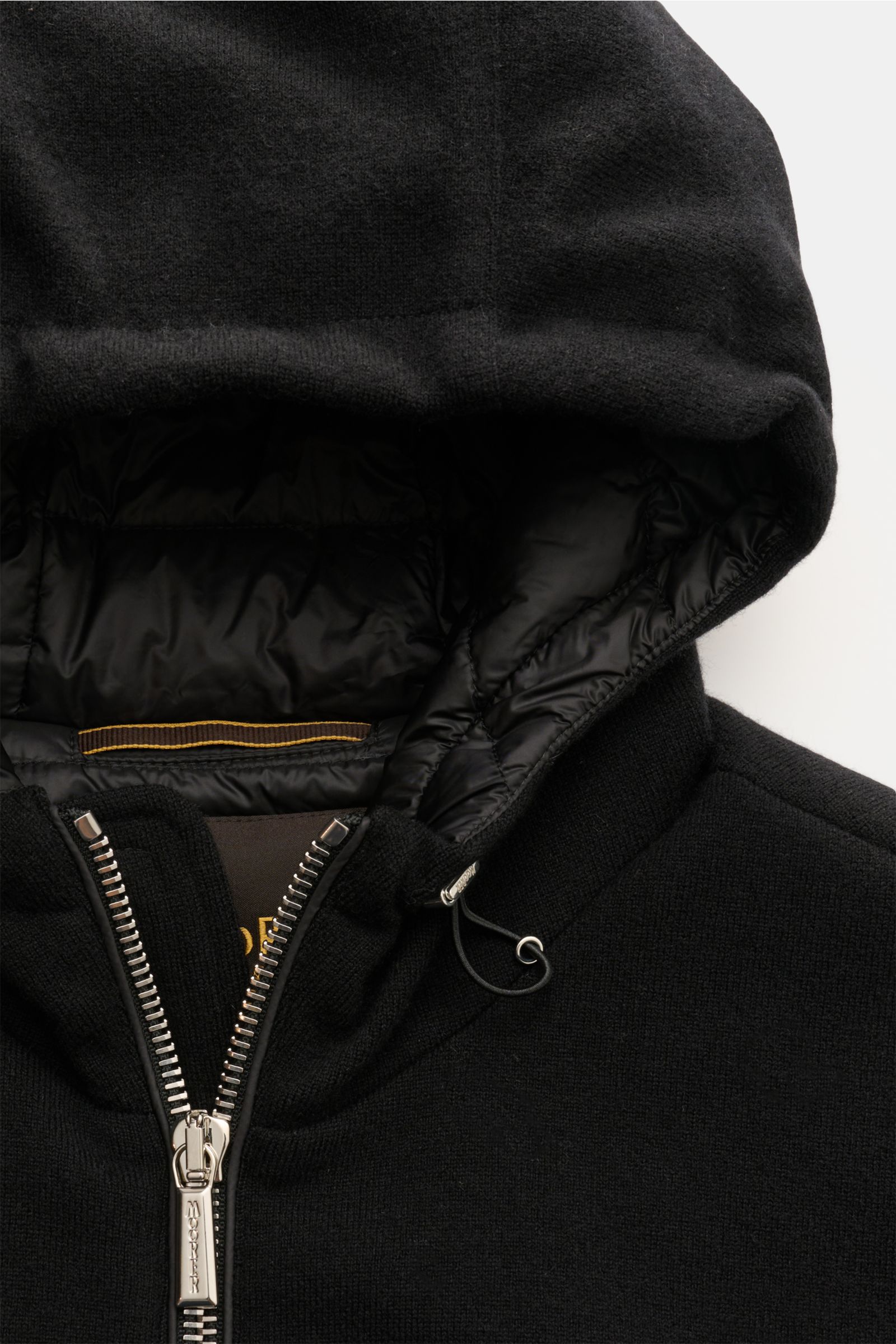 Close-up front view of the hood and zipper of the Moorer Cashmere Daunenblouson 'Brigno' schwarz, showing black baby-cashmere exterior and quilted inner lining with silver zipper. Leichte, wärmende Qualität: Der sportive Daunenblouson 'Brigno' verfügt 