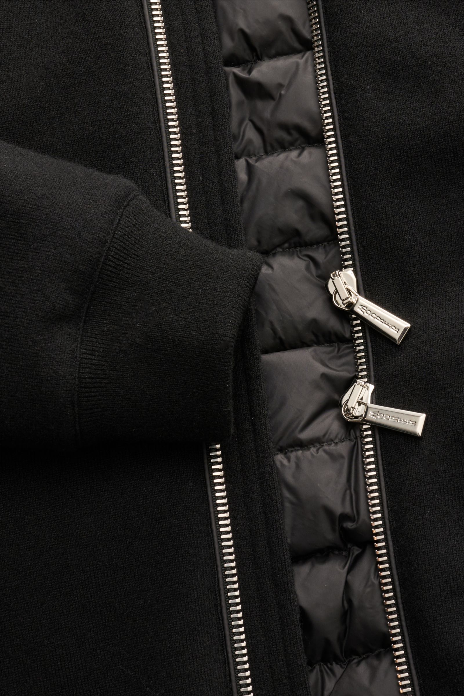 Close-up front view of the Moorer Cashmere Daunenblouson 'Brigno' schwarz showing the soft baby-cashmere outer fabric, slim fit sleeve cuff, and dual silver zippers revealing the lightweight, warm down filling. Leichte, wärmende Qualität: Der sportive 