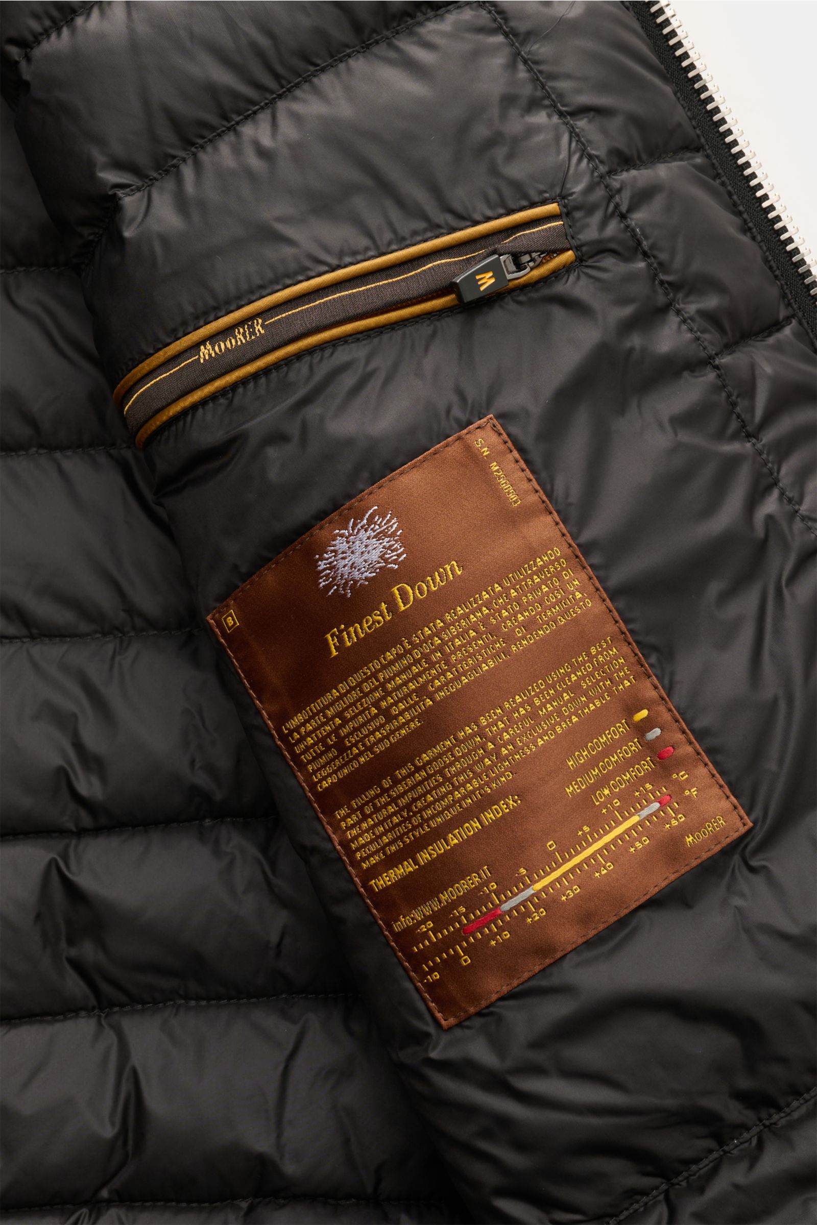 Close-up inside view of Moorer Cashmere Daunenblouson 'Brigno' schwarz showing black quilted lining, brown label, and zippered pocket.

Description: Leichte, wärmende Qualität: Der sportive Daunenblouson 'Brigno' verfügt über eine wärmende Daunenfüllun