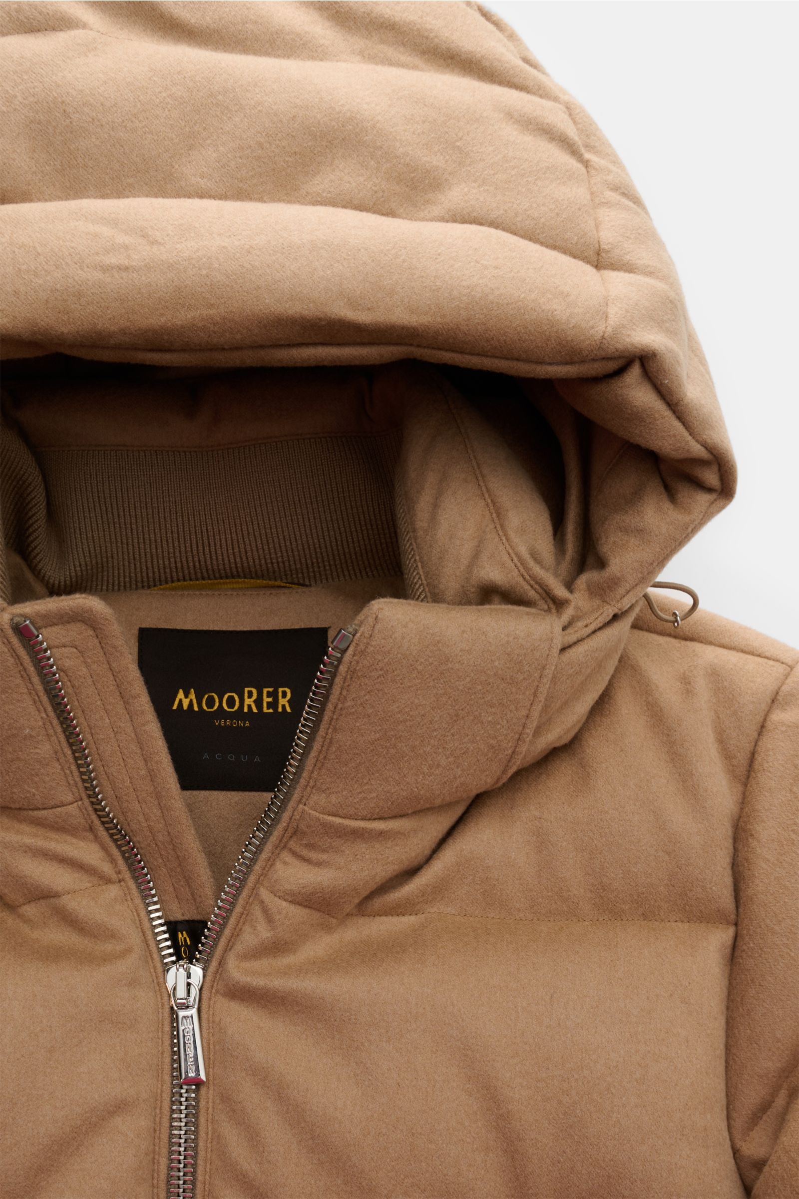 Nahaufnahme der Moorer Daunenjacke 'Valls' camel von oben, zeigt Kapuze, Steppung, zwei-Wege-Reißverschluss, weiche Kamelwolle, wattierte Kapuze, Taschen, Slim Fit für Wärme bis -12 °C.