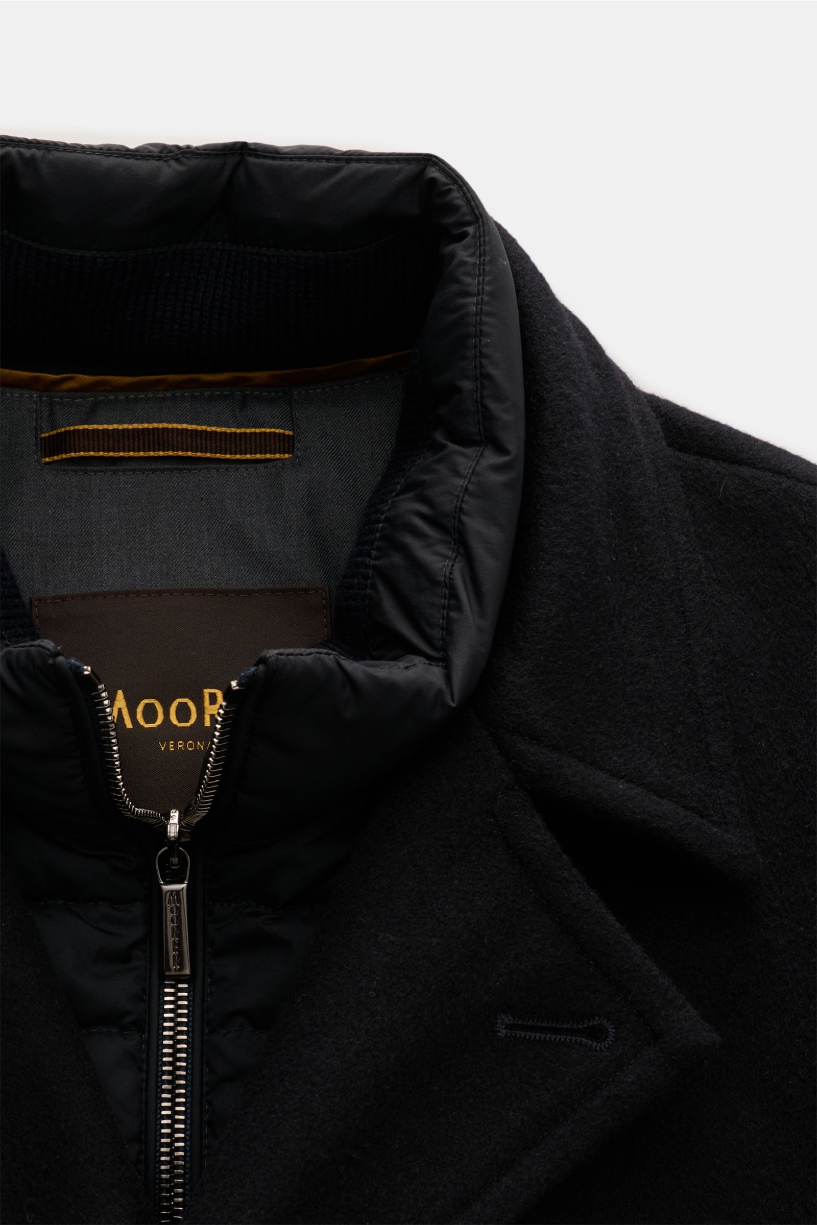 Close-up front view of Moorer Jacke 'Volmer-Kn' navy showing elastic microfiber, water-repellent double-front with two-way zipper, leather trim, slim fit, concealed hood in collar, slanted welt pockets, buttoned sleeve cuffs, shiny lining, and two zipper 
