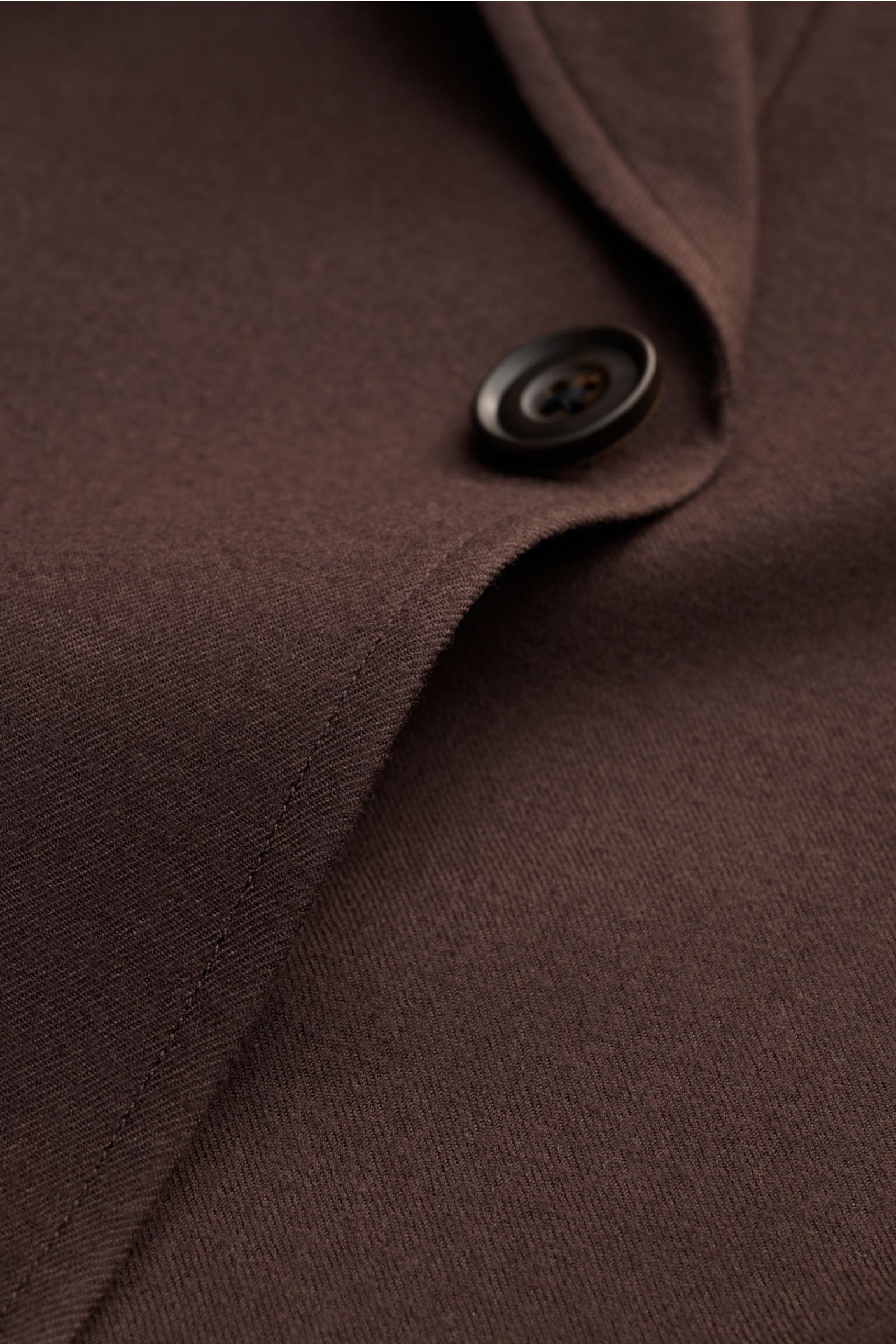 Nahaufnahme der dunkelbraunen Corneliani Jacke aus leichter Schurwolle mit fallendem Revers und Vier-Knopf-Leiste, weicher Griff.