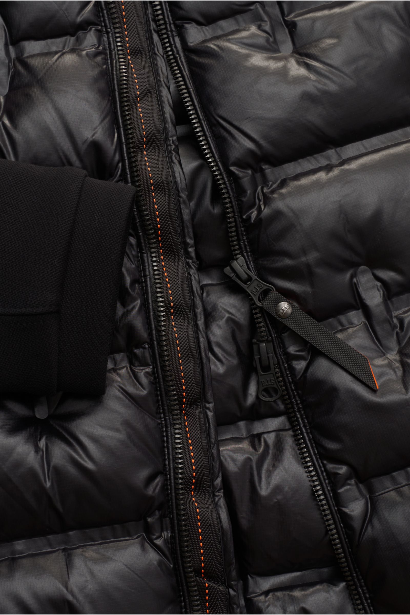 Nahaufnahme der schwarzen Parajumpers Daunenjacke 'Gyles' mit glänzendem Ripstop-Material, gesteppter Slim-Fit-Optik, Reißverschluss und Jersey-Ärmelbündchen.