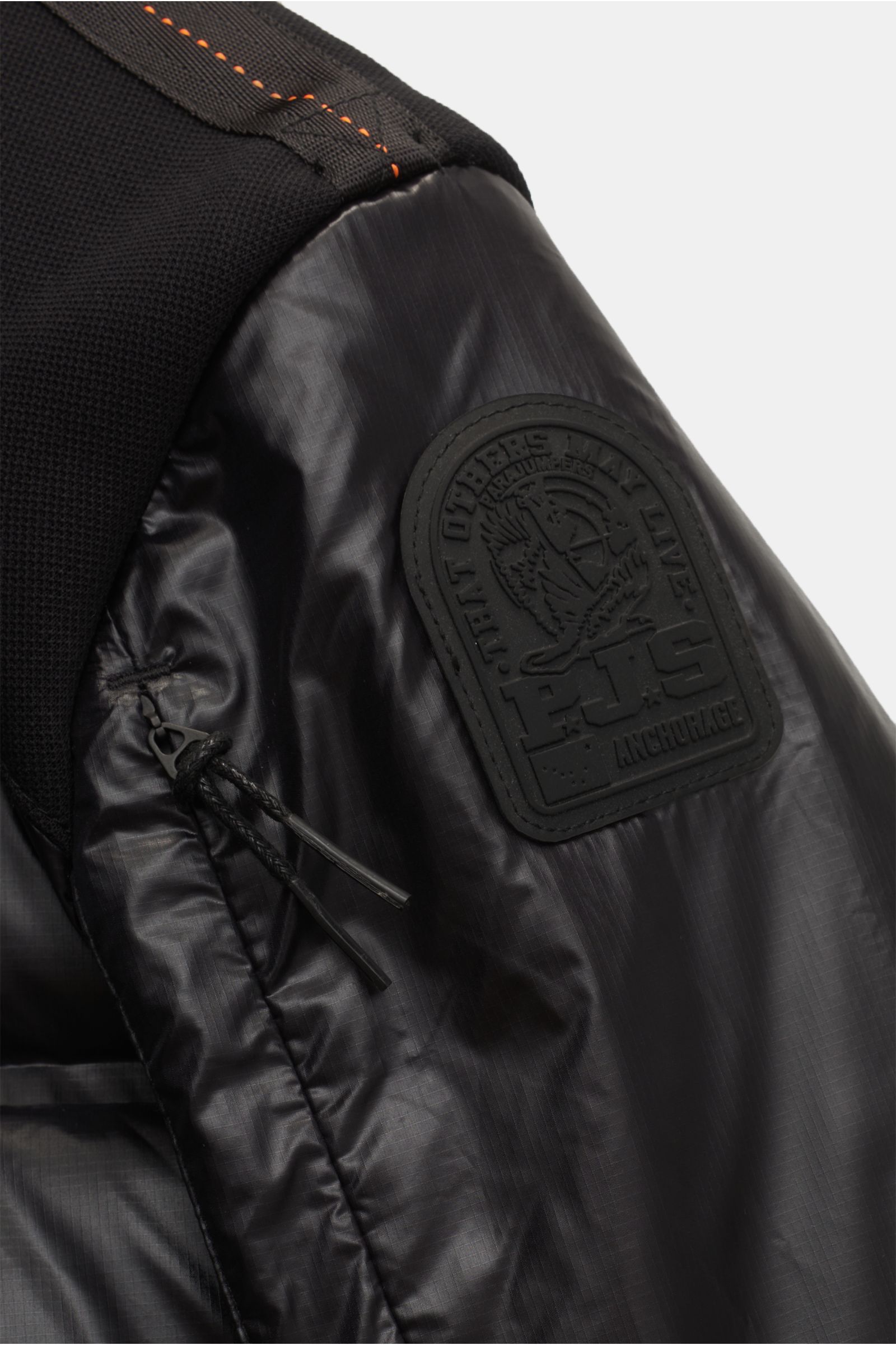 Nahaufnahme der Ärmelpartie der Parajumpers Daunenjacke 'Gyles' schwarz, glänzende Ripstop-Microfaser mit gummiertem Patch, robustem Jersey und Zipper-Tasche am Oberarm.