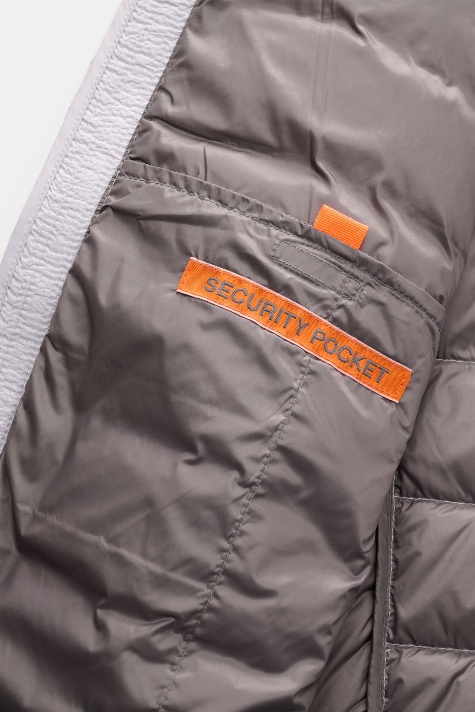 Close-up view of the inner security pocket with orange label on the Parajumpers Daunenjacke 'Ugo' hellgrau, featuring ultralight down fill and durable microfiber. Lässiges Design und ein klares Statement für Nachhaltigkeit: Die Jacke 'Ugo' von PARAJUMPERS