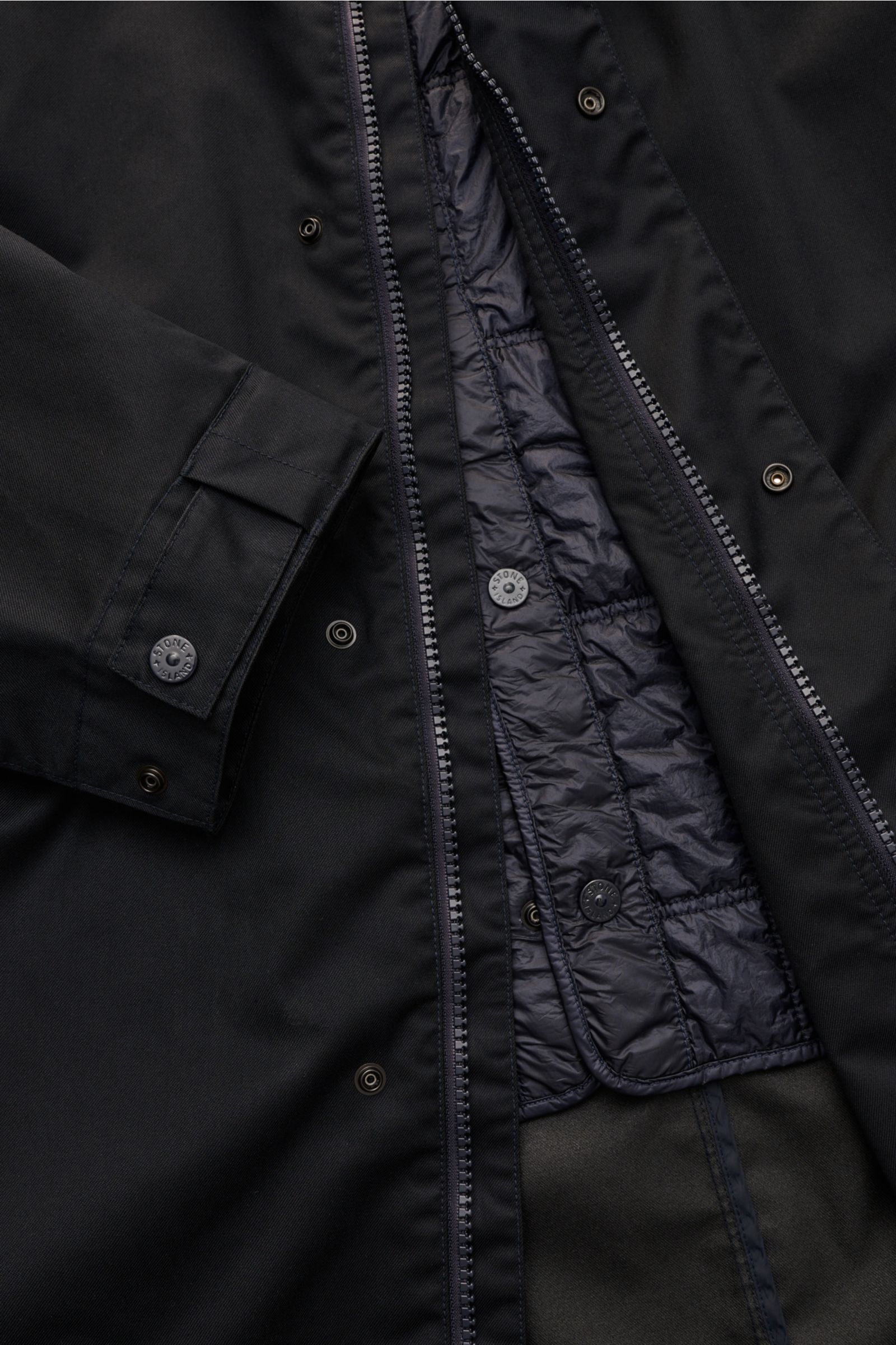 Nahaufnahme von geöffnetem Stone Island Parka 'Twill Wool-TC Ghost Piece' navy, zeigt reines Wollmaterial, herausnehmbares Innenfutter mit veganer Primaloft-Füllung und Details wie Druckknöpfe und Reißverschluss.