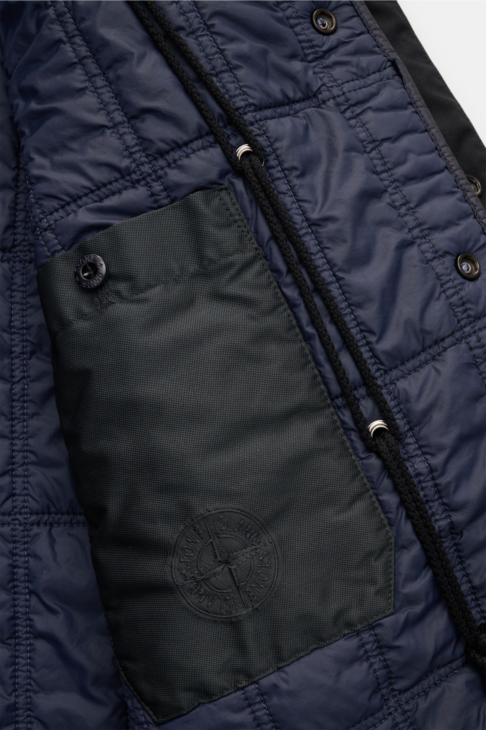 Nahaufnahme des Innenfutters vom Stone Island Parka 'Twill Wool-TC Ghost Piece' navy, mit veganer Primaloft-Füllung, Innentasche und Kompass-Badge.