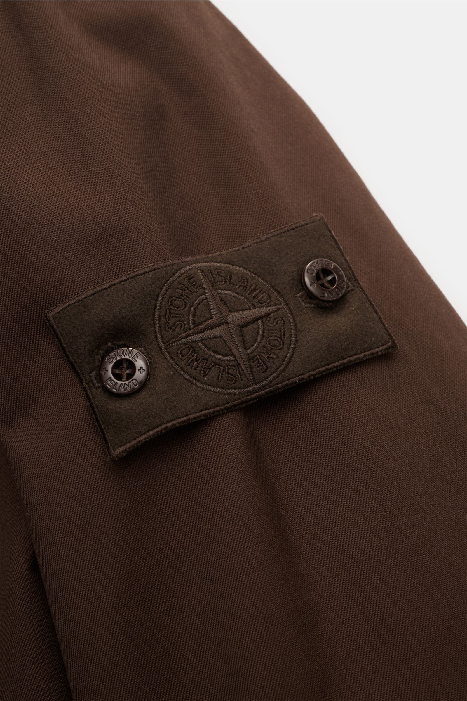Stone Island Parka 'Twill Wool-TC Ghost Piece' dunkelbraun, Detailaufnahme des tonalen Kompass-Badges an Ärmel aus reiner Wolle.