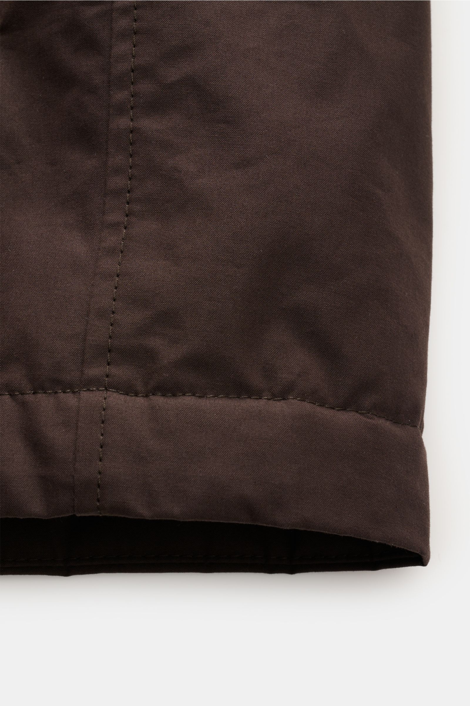 Alt-Tag (124 Zeichen): Nahaufnahme des Ärmelabschlusses der dunkelbraunen Stone Island Jacke 'Weatherproof Cotton Canvas Ghost Piece' aus Baumwoll-Canvas.