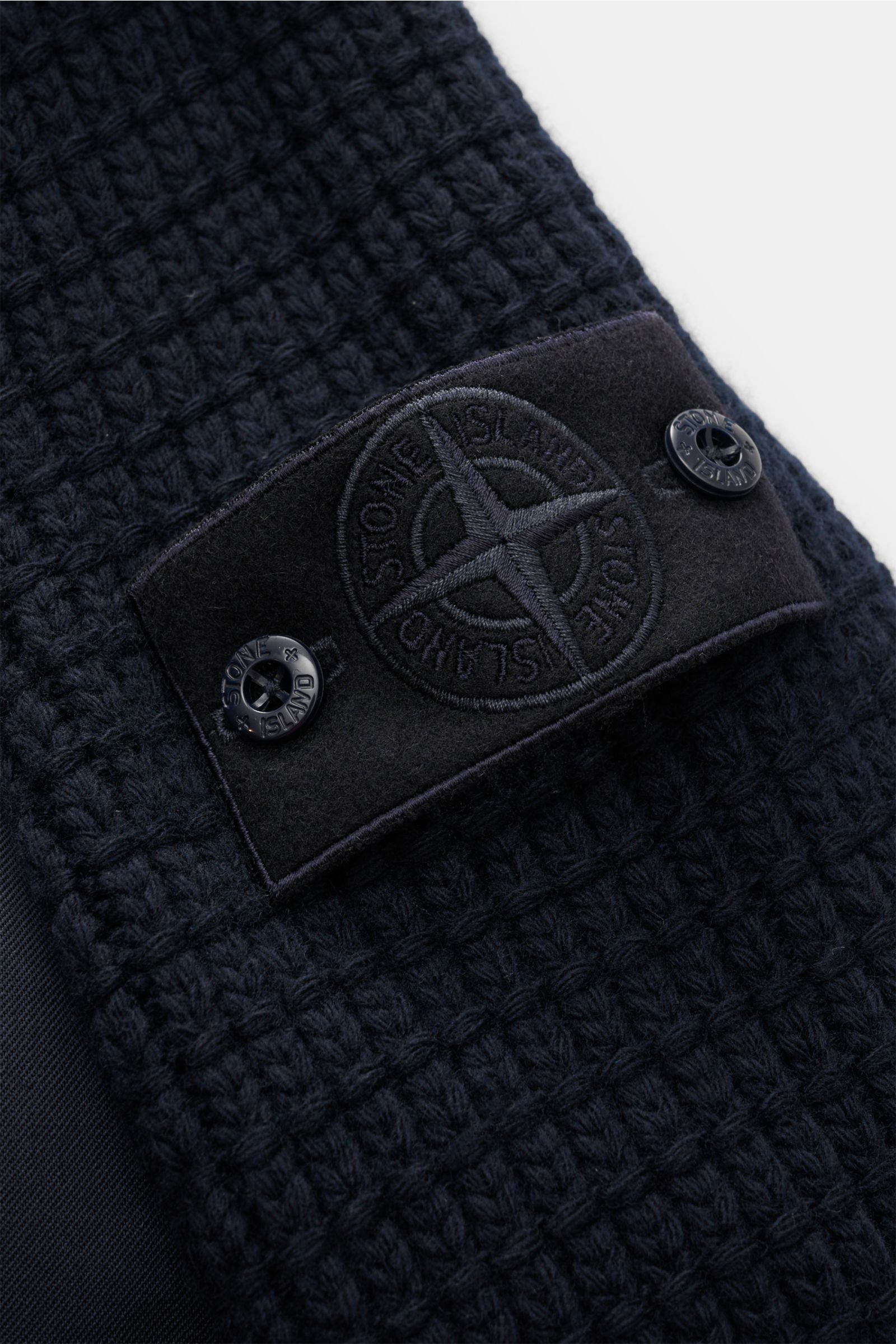 Close-up front-side view of the Stone Island Daunenjacke 'Twill Wool-TC Ghost Piece' navy, showing its textured knit sleeves with the embroidered black logo patch and buttons. Monochromes Statement-Piece für die Übergangszeit: Die Daunenjacke aus der 'Gho