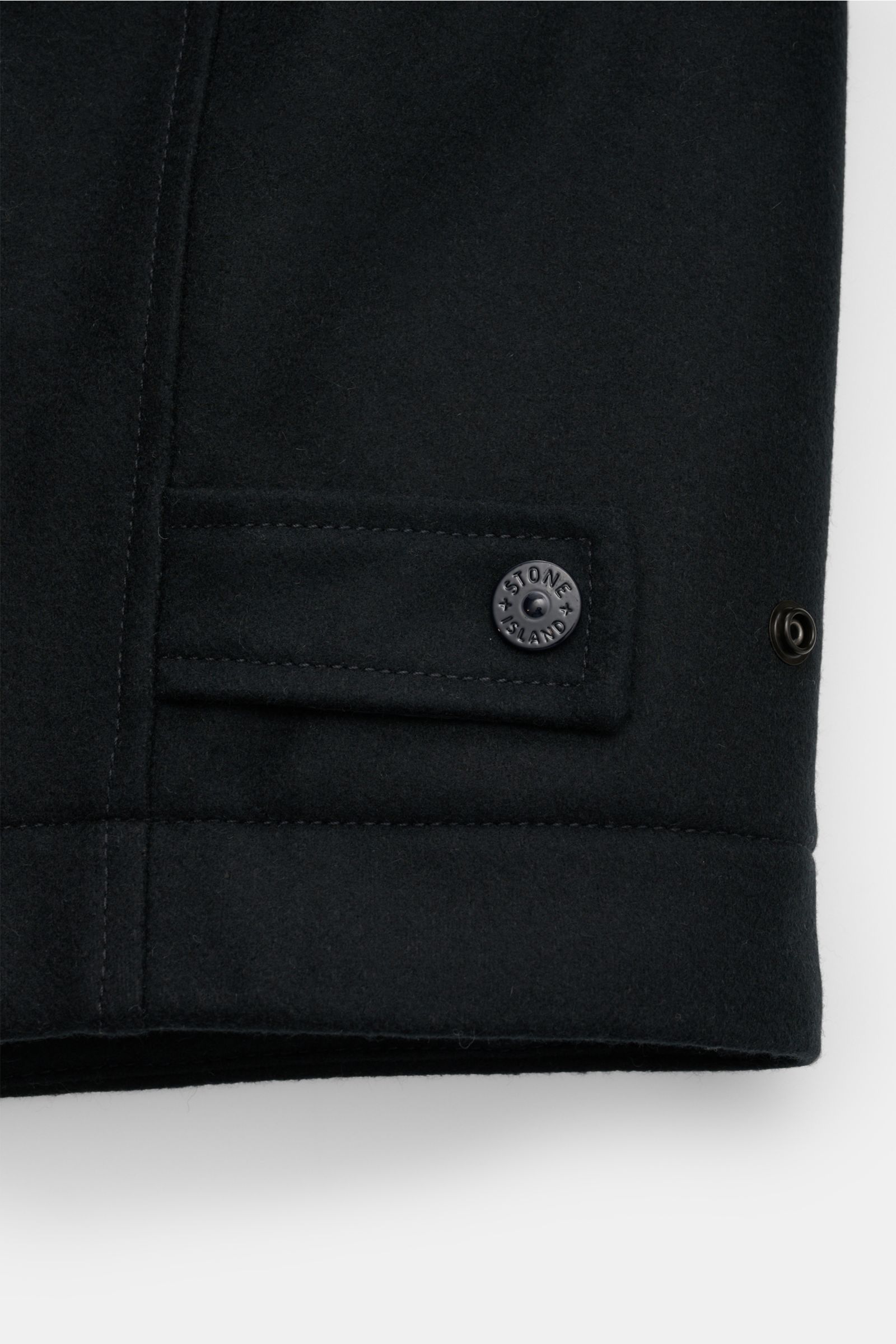 Close-up side view of Stone Island Jacke 'Wool Nylon Flannel Ghost Piece' navy showing water-repellent wool-nylon flannel, tonal badge, adjustable waist tab with button, and fine stitching. Monochrome Herbst-Looks: Diese Jacke aus der 'Ghost'-Capsule-Coll