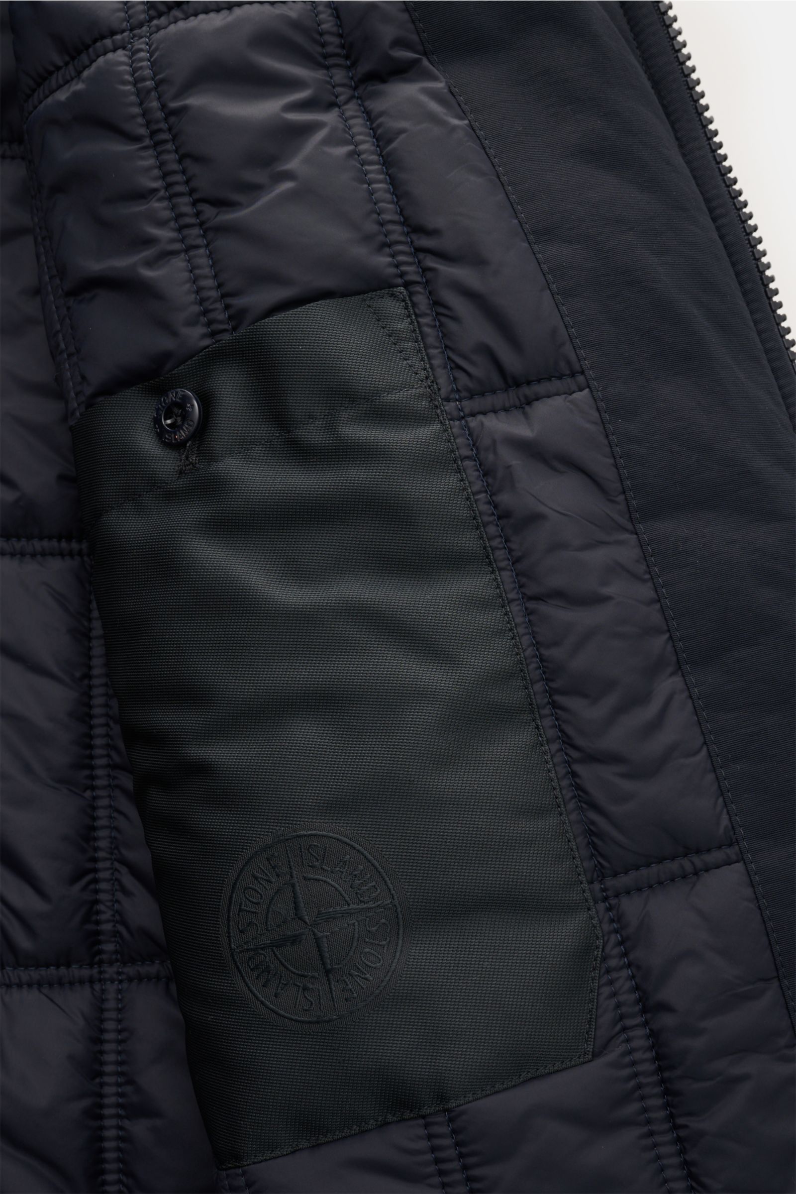 Close-up interior view of Stone Island Jacke 'Wool Nylon Flannel Ghost Piece' navy showing quilted lining, inner pocket with tonal compass badge, and snap button. Monochrome Herbst-Looks: Diese Jacke aus der 'Ghost'-Capsule-Collection von STONE ISLAND wir