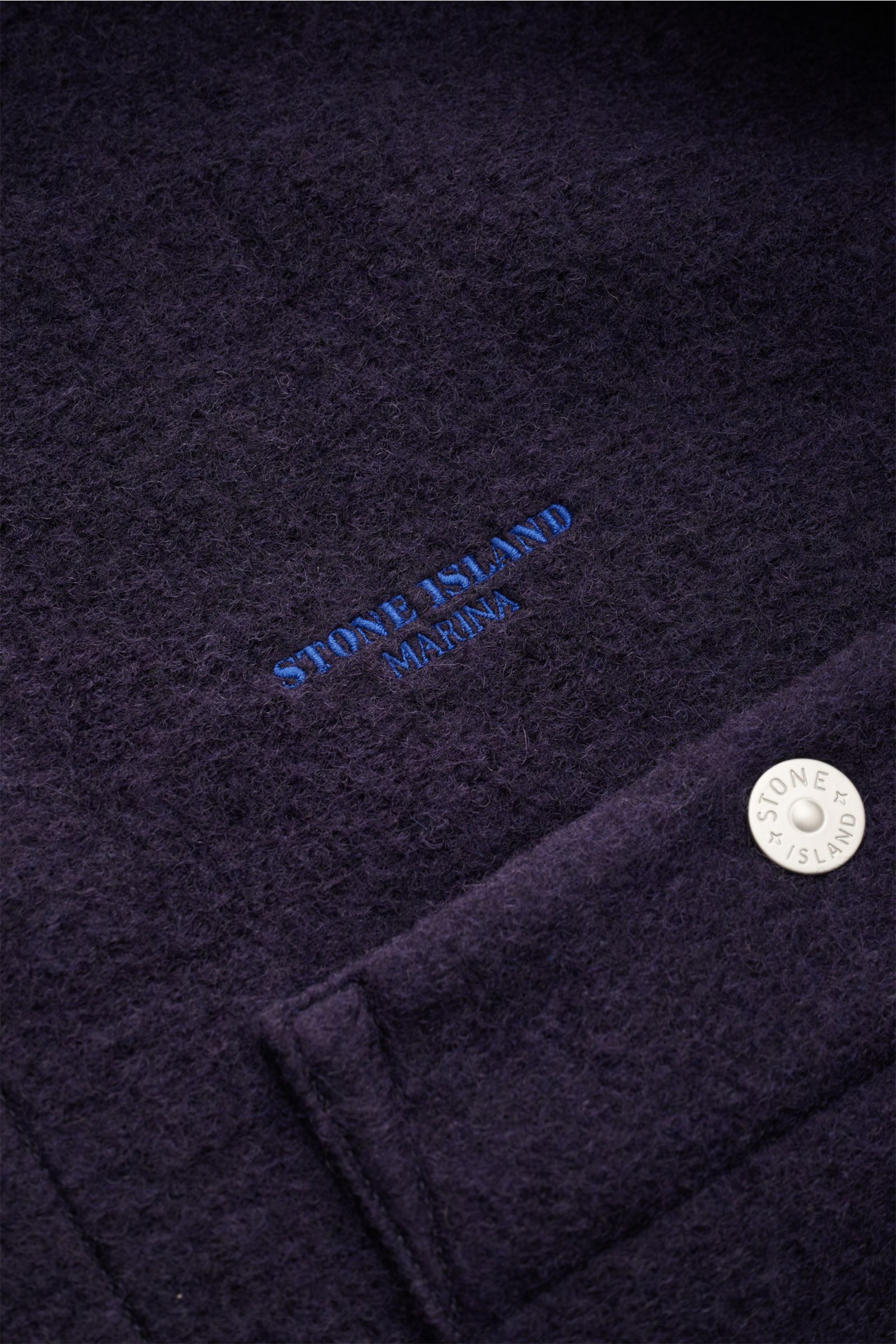 Close-up front view of Stone Island Jacke 'Marina Felted Wool Polyester S.I. Marina' navy, showing felted wool texture, blue embroidery, and silver button. -

gefilzte Wolle
leicht griffige Qualität
wasserabweisend
