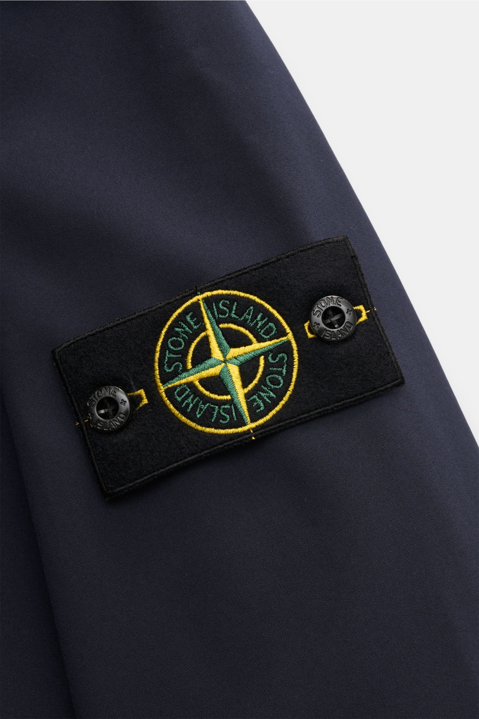 Close-up of the Stone Island Softshell-Blouson 'Light Soft Shell-R e.dye Technology' navy, showing the embroidered compass badge on the sleeve from a side angle. 

Ob für sportliche Aktivitäten oder als Casual-Allrounder, auf die wind- und wasserabweis