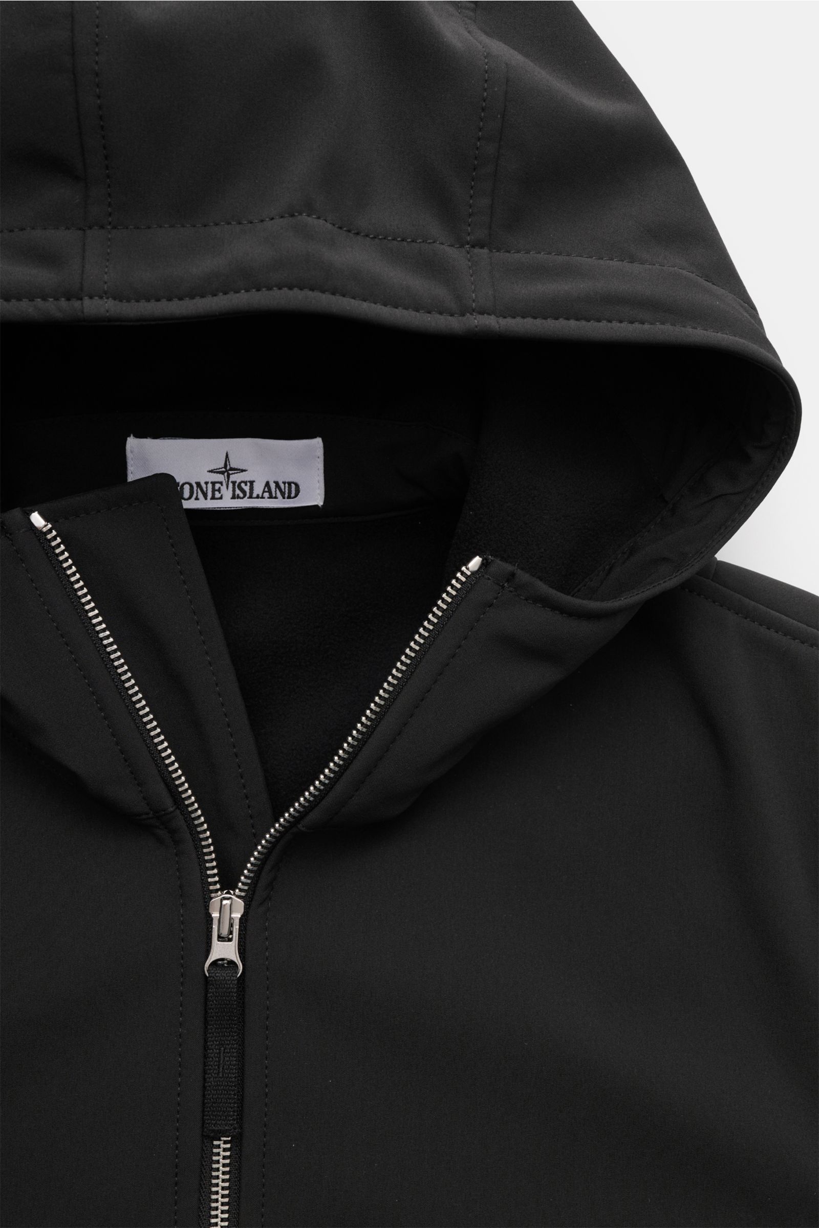 Close-up front view of the Stone Island Softshell-Blouson 'Light Soft Shell-R e.dye Technology' schwarz hoodie showing zipper, hood, and label, made of elastic microfiber with a smooth touch, wind- and water-repellent, breathable, slim fit, robust two-way