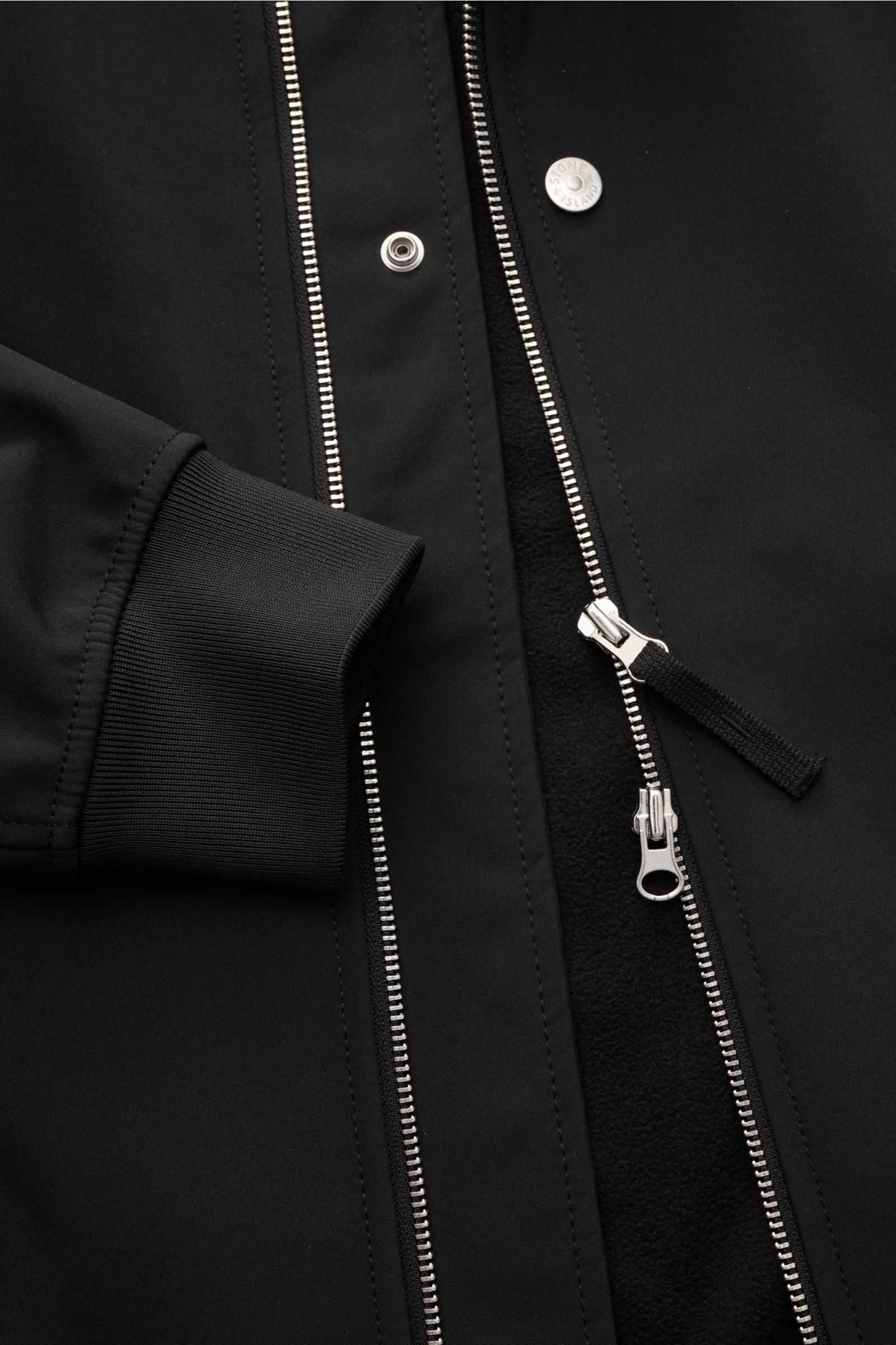 Close-up front view of Stone Island Softshell-Blouson 'Light Soft Shell-R e.dye Technology' schwarz showing elastic microfiber cuff, robust two-way zipper, and snap button.

Ob für sportliche Aktivitäten oder als Casual-Allrounder, auf die wind- und wa