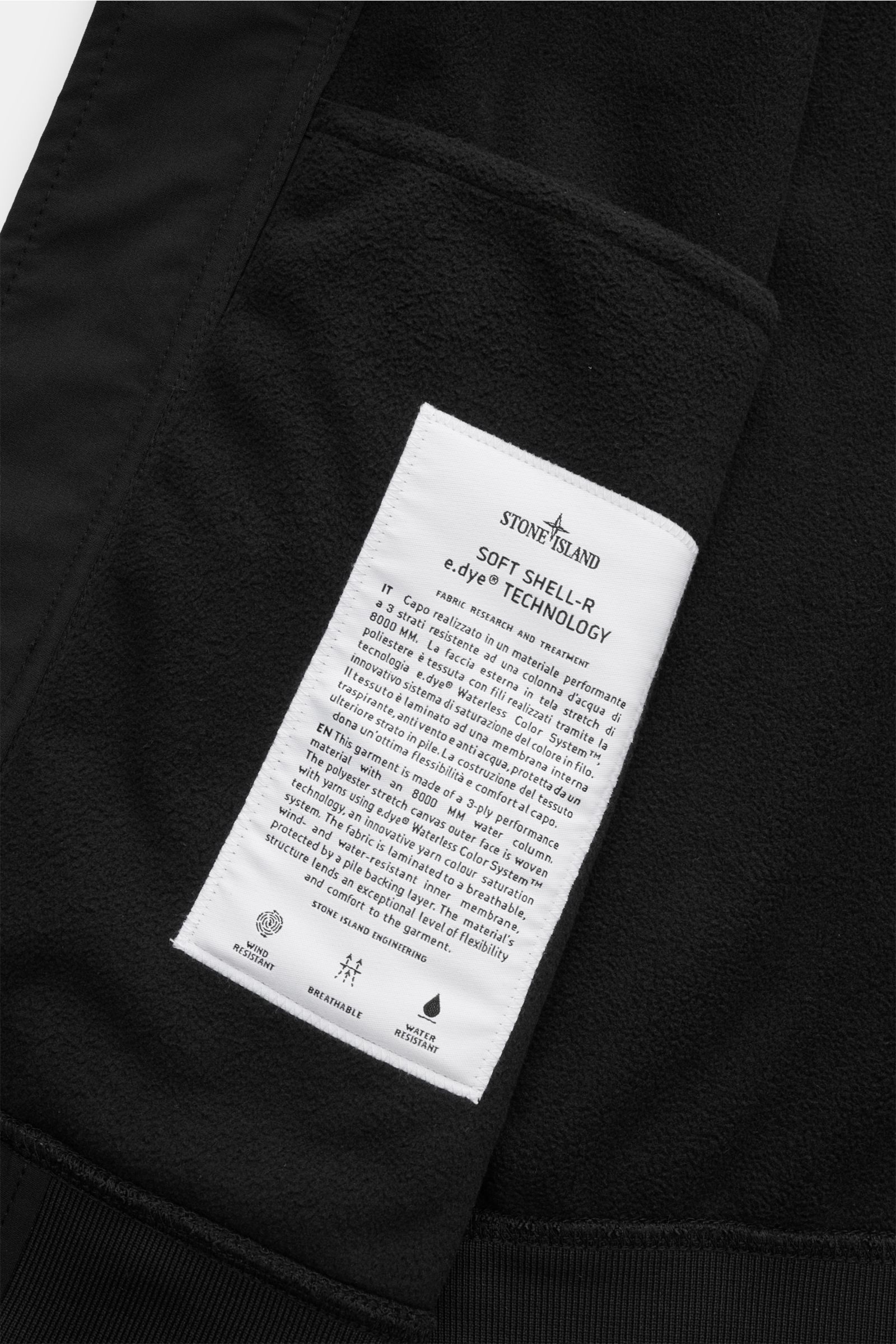 Close-up view of the inner label on the Stone Island Softshell-Blouson 'Light Soft Shell-R e.dye Technology' schwarz, showing fabric details and care information on the wind- and water-resistant, breathable softshell jacket with elastic microfiber, smooth