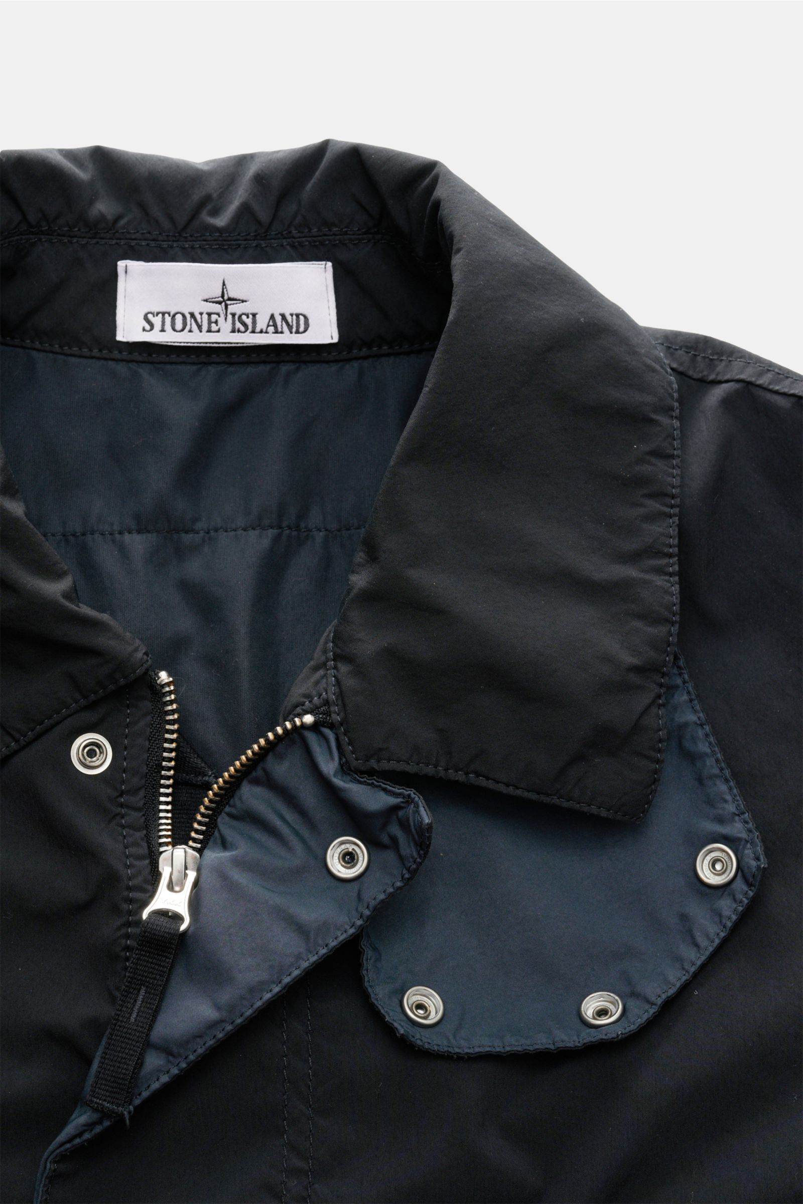 Stone Island Jacke 'Light Compact Touch Poly-TC' navy, Nahaufnahme von Kragen mit Reißverschluss, Druckknöpfen und Label, wasserabweisend, elastisch, weich.