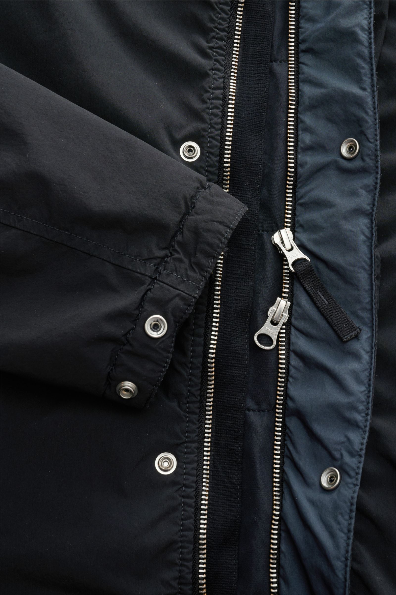Nahaufnahme der Stone Island Jacke 'Light Compact Touch Poly-TC' navy von innen mit Reißverschluss, Druckknöpfen und elastischem Ärmelabschluss.