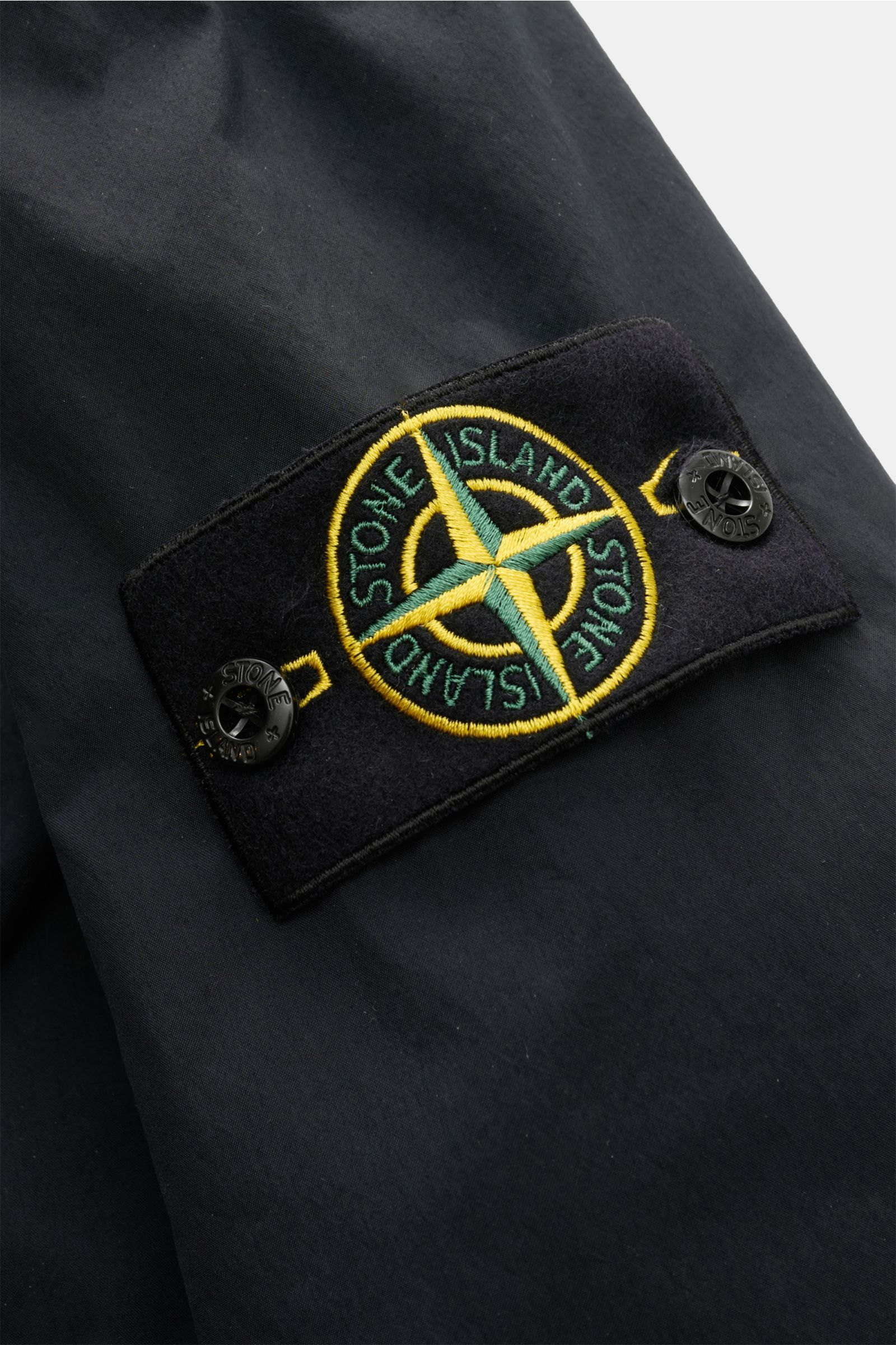 Stone Island Jacke 'Light Compact Touch Poly-TC' navy in Nahaufnahme seitlich, zeigt typisches Kompass-Badge, wasserabweisend, elastische Microfaser, Regular Fit.