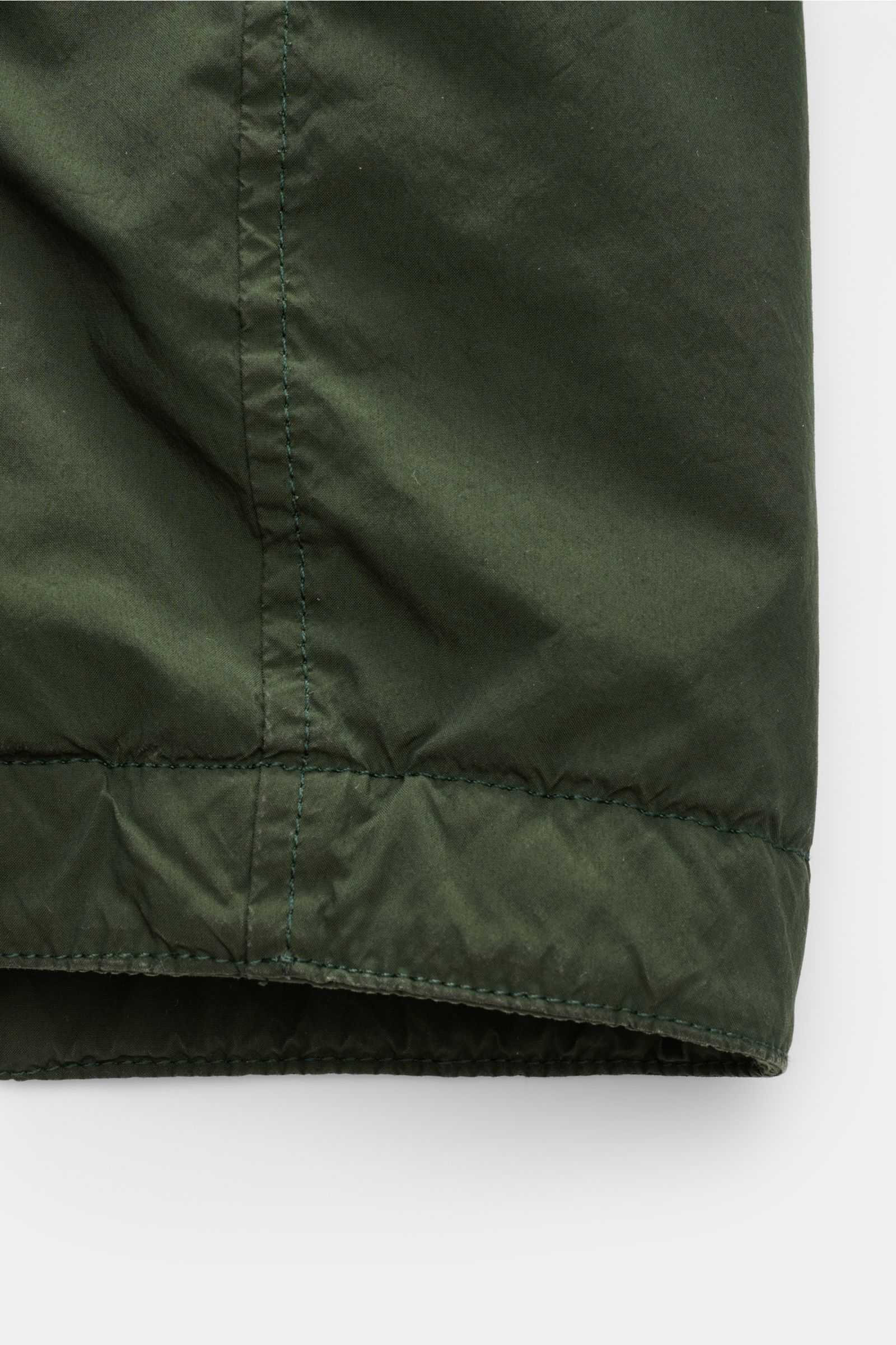Stone Island Jacke 'Light Compact Touch Poly-TC' dunkelgrün, Detailaufnahme des unteren Saums mit elastischer Microfaser, wasserabweisend und wattiert.