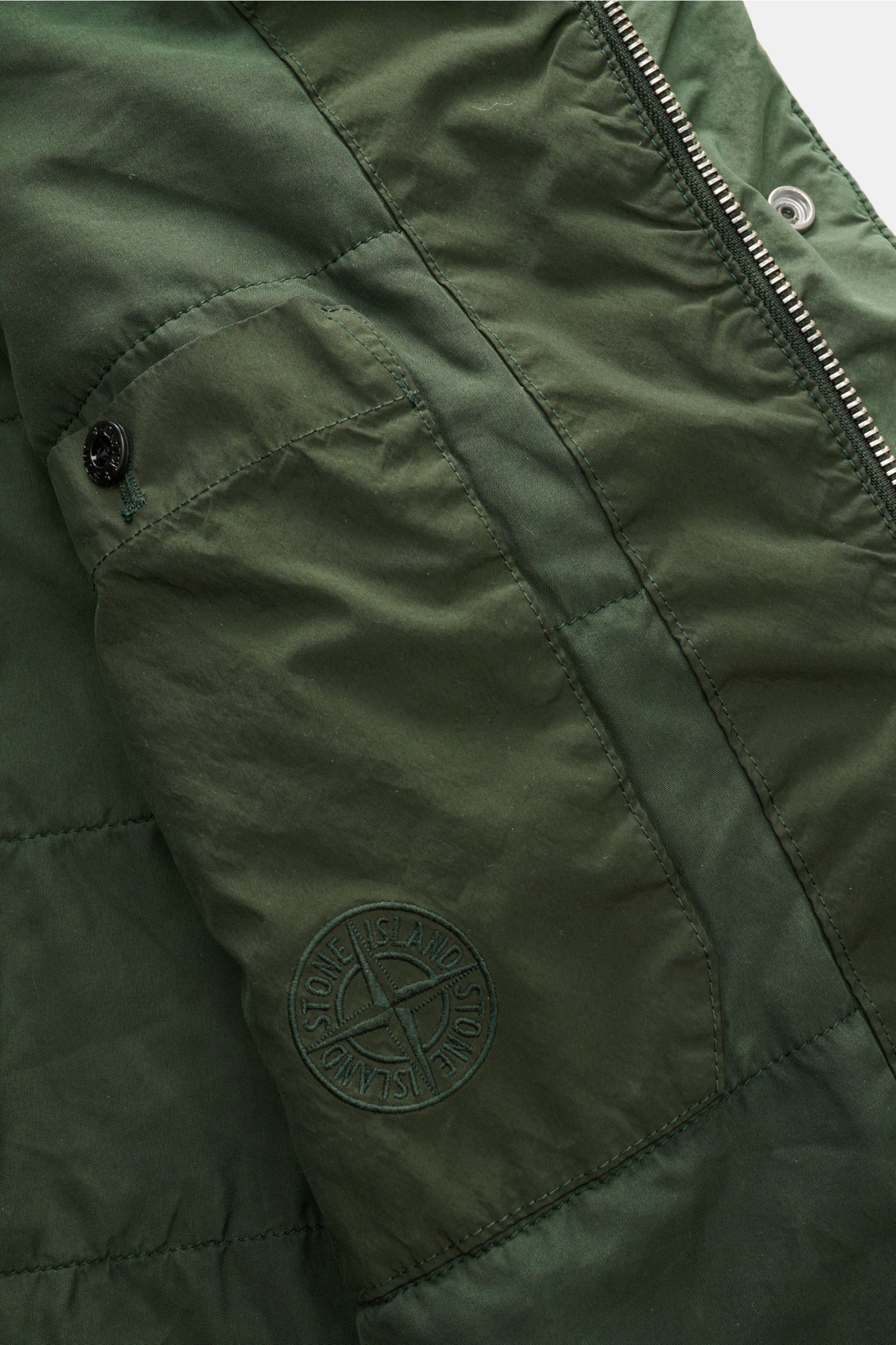 Stone Island Jacke 'Light Compact Touch Poly-TC' dunkelgrün, Detailaufnahme Ärmel mit Kompass-Badge, wasserabweisend, elastisch, wattiert.