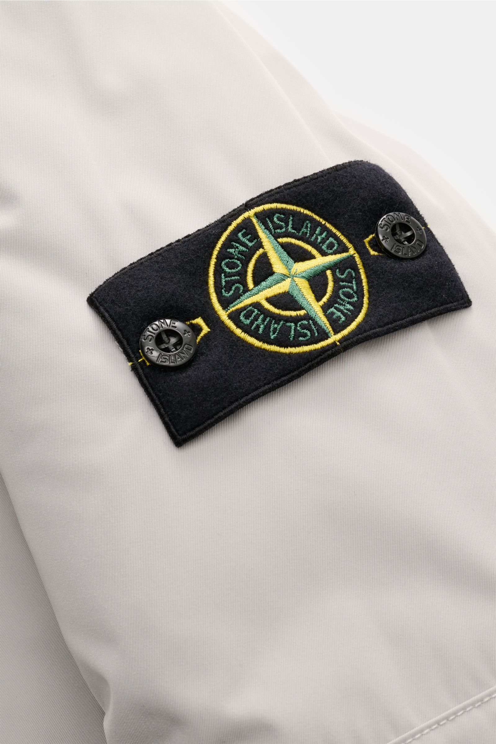 Stone Island Daunenparka 'Micro Twill Down' sand, Detailaufnahme des Kompass-Badges auf weichem, wasserabweisendem Microfaser-Twill.