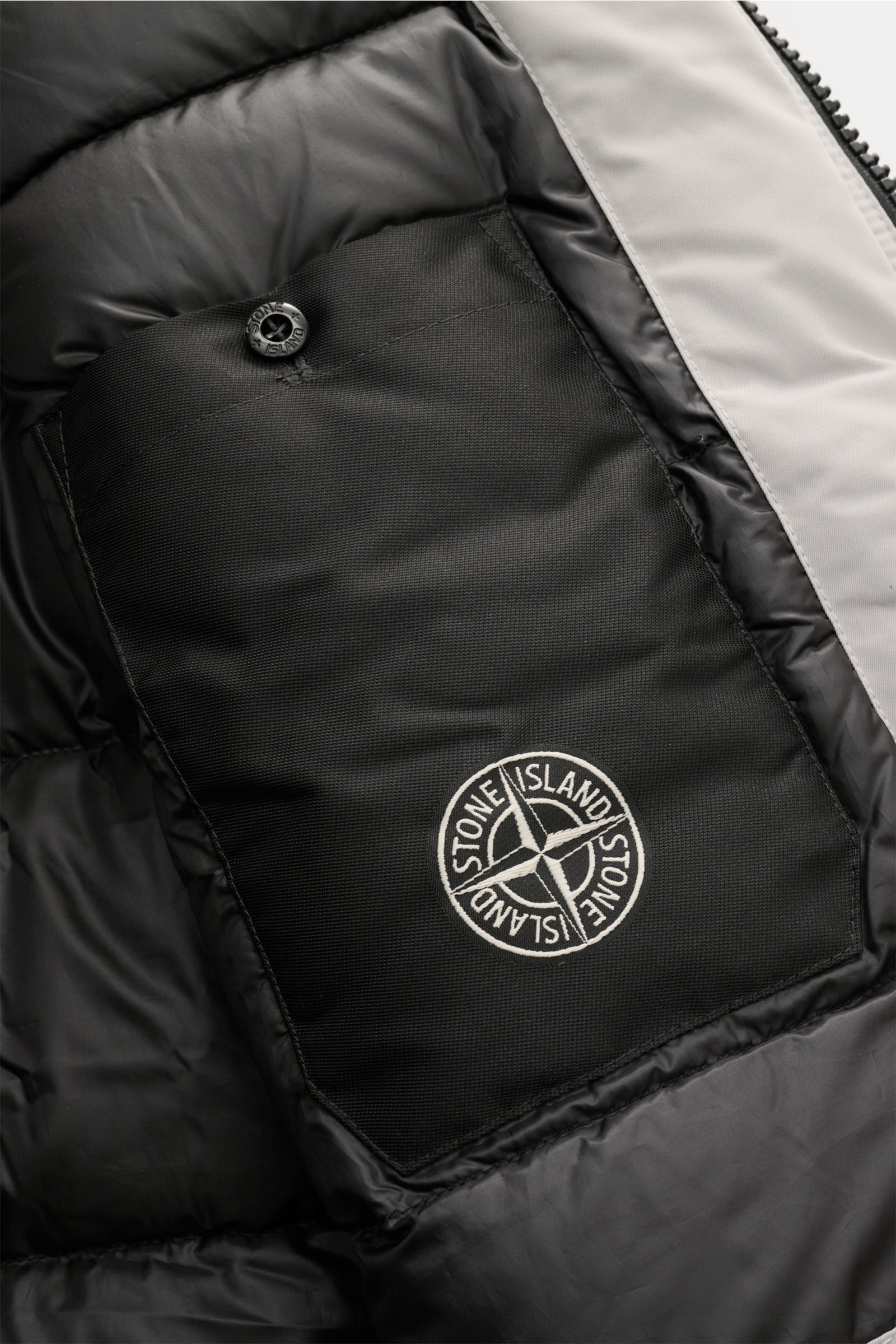 Nahaufnahme der Innentasche mit Kompass-Badge des Stone Island Daunenparka 'Micro Twill Down' sand, Detailfoto von innen.