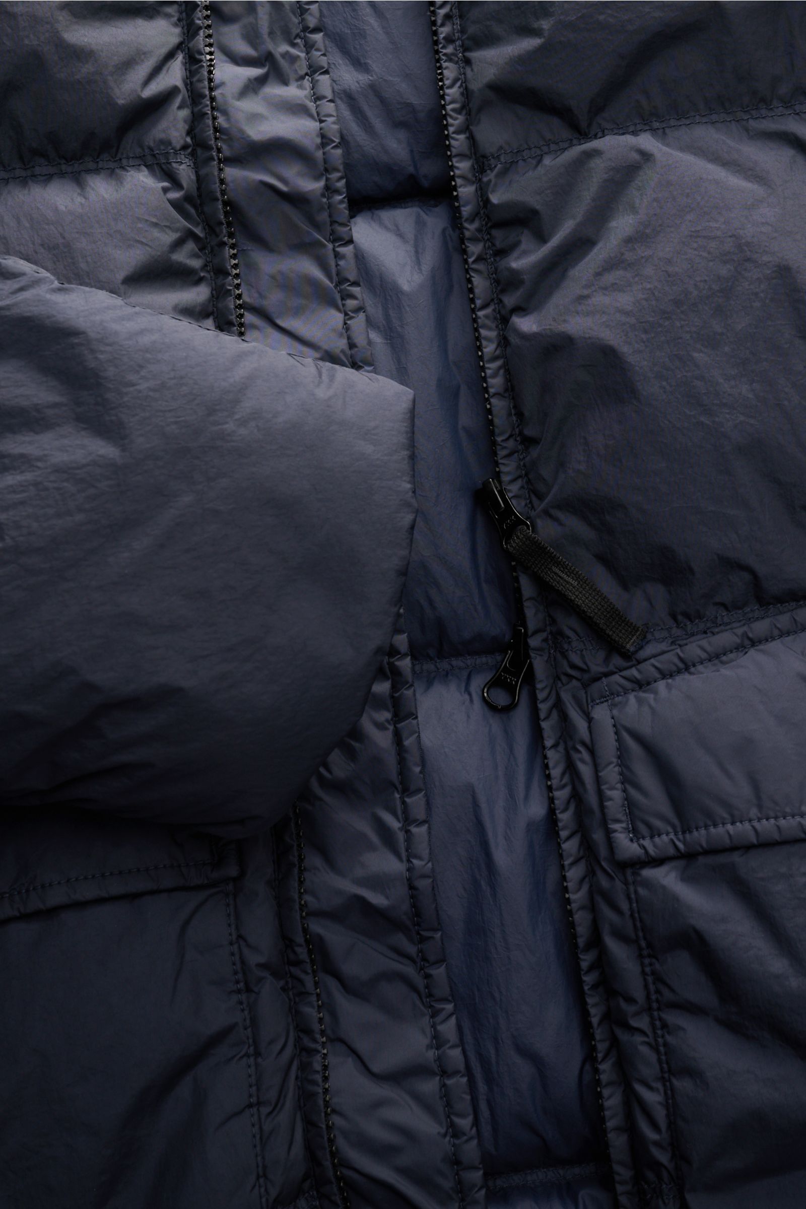 Close-up view of the Stone Island Daunenjacke 'Garment Dyed Crinkle Reps NY' navy, showing coated microfiber fabric, two-way zipper, and pockets. The jacket features a wind- and water-repellent finish, padded with warm down, garment-dyed slim fit, hood wi