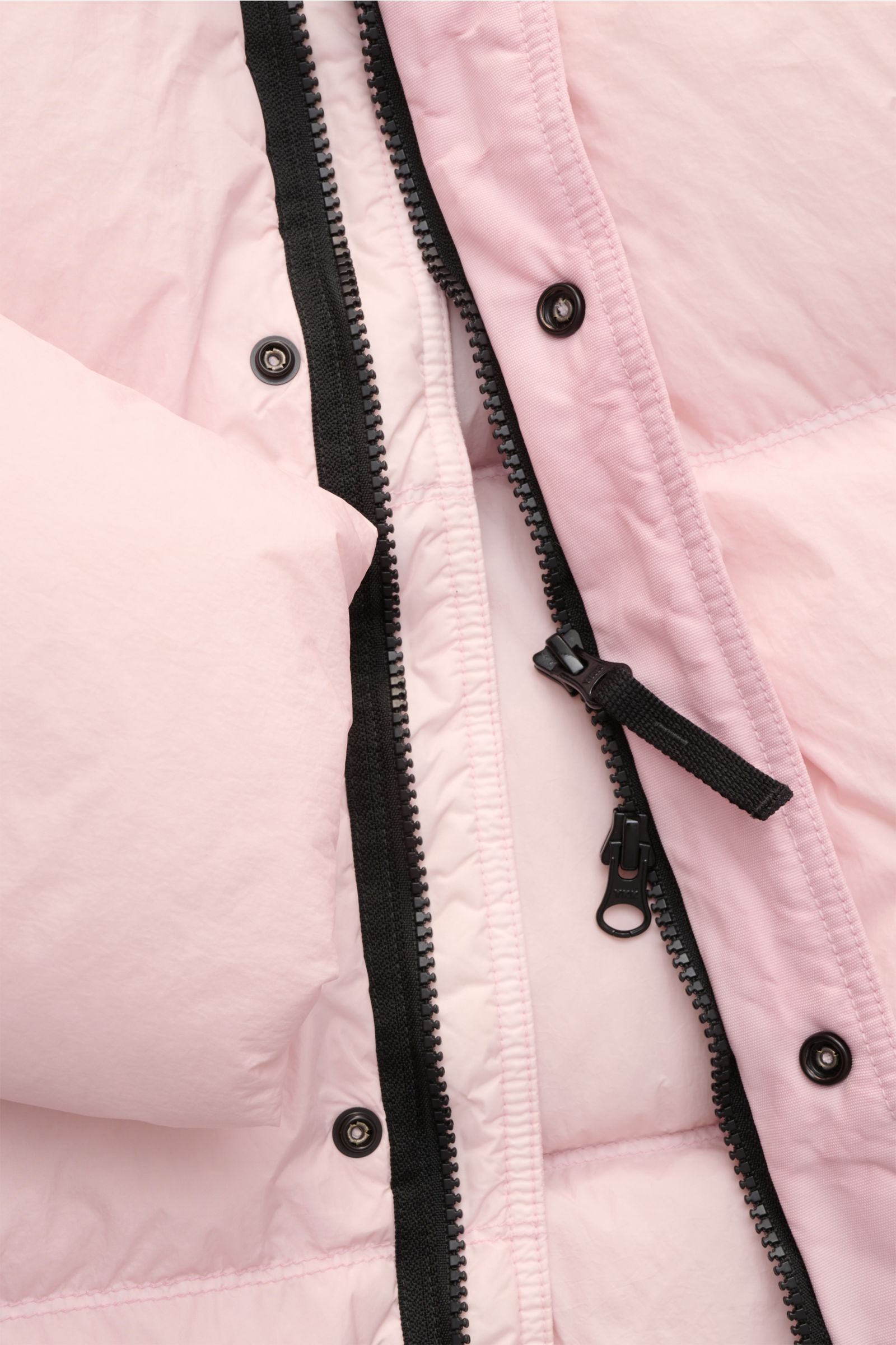 Close-up front view of the Stone Island Daunenjacke 'Garment Dyed Crinkle Reps NY' rosé, showing the black two-way zipper, snap buttons, and light pink coated crinkle microfiber fabric with warm down filling, windproof features, and garment-dyed finish.