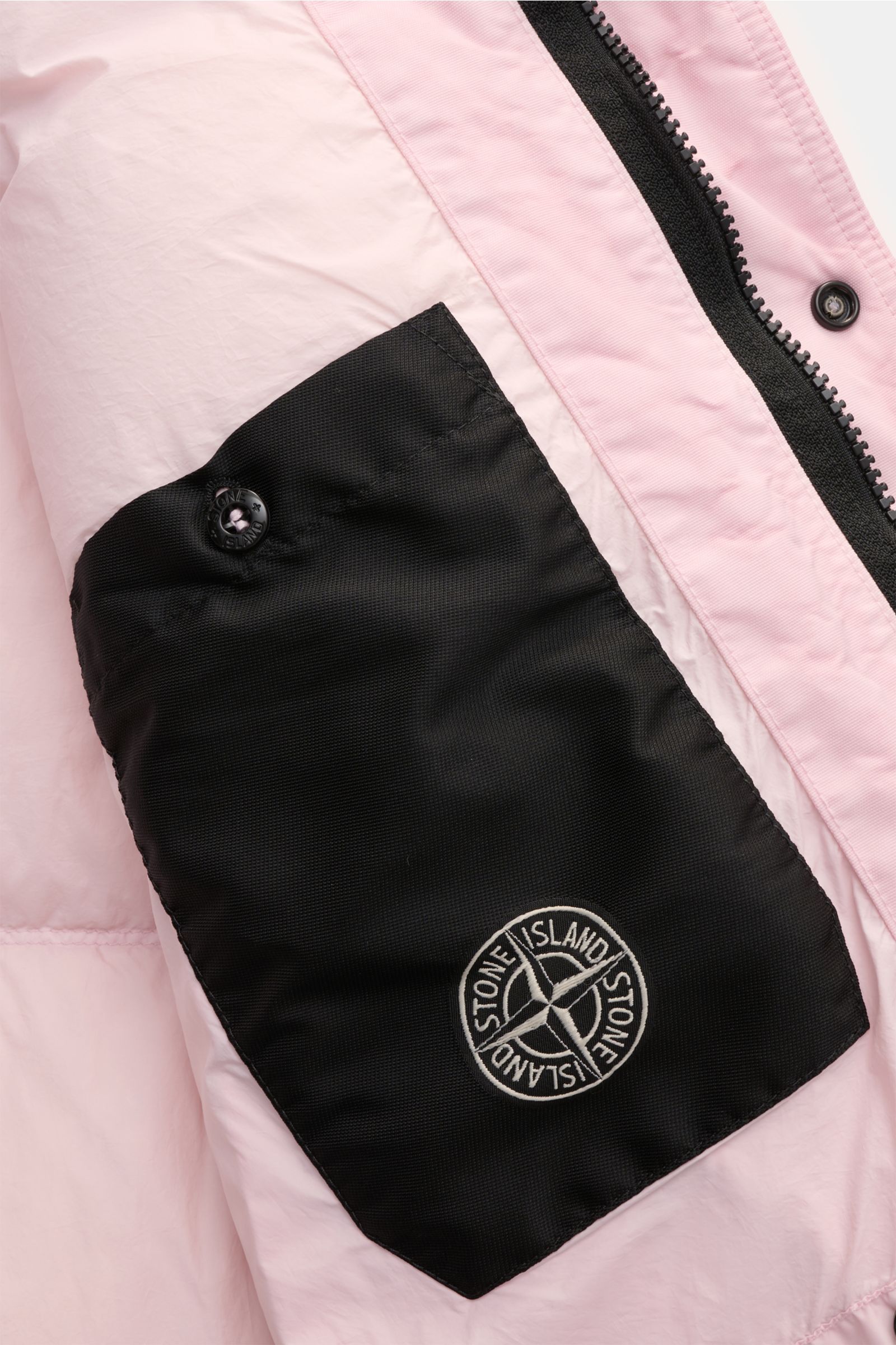 Close-up front view of Stone Island Daunenjacke 'Garment Dyed Crinkle Reps NY' rosé, showing pink crinkle microfiber, black inner pocket with logo, zip, and snap button.