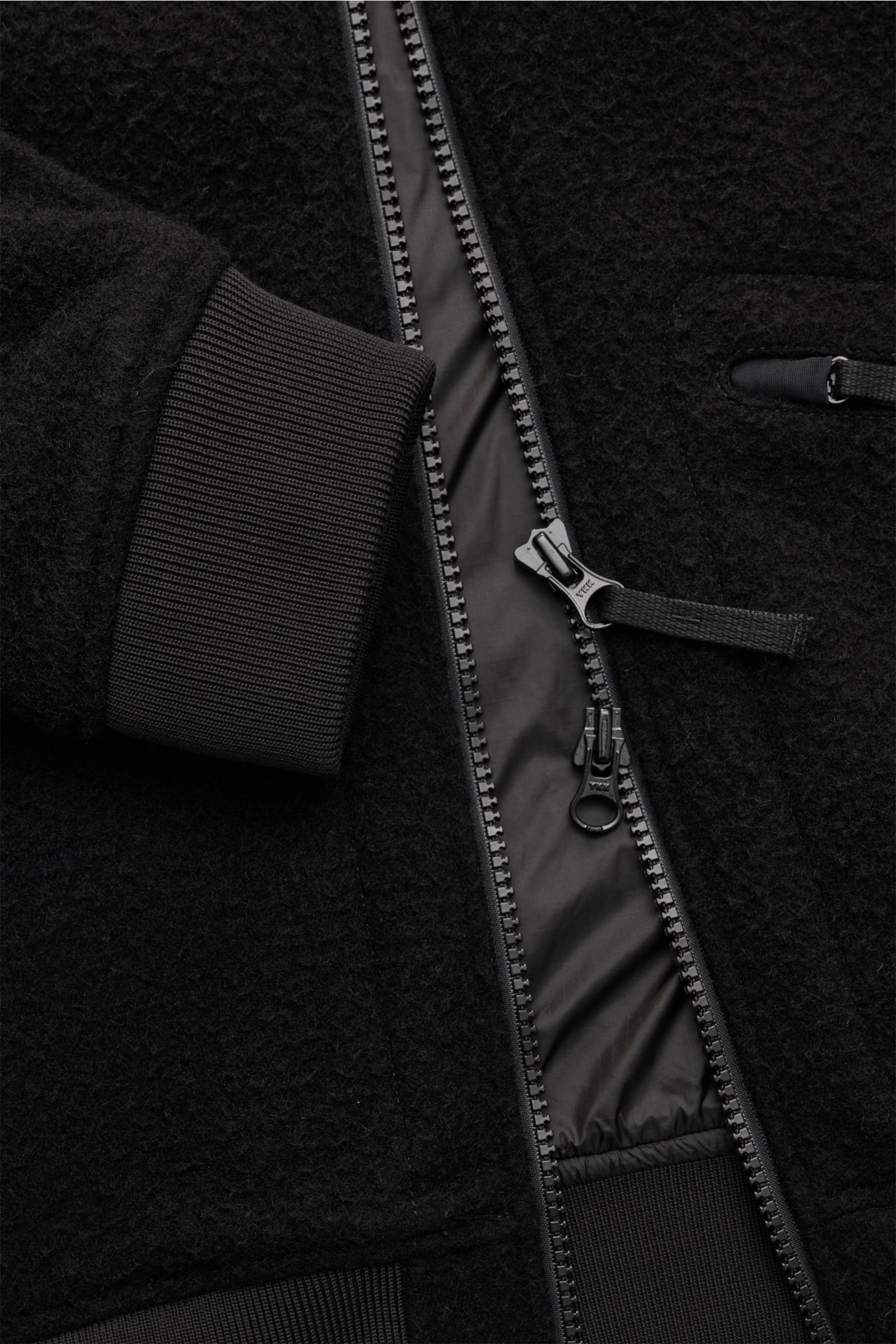 Close-up front view of the Stone Island Blouson 'Panno Ratinato' schwarz showing the black wool-mix textured fabric, rib-knit cuff, two-way zipper, and zippered hip pocket, highlighting its sportiv design and vintage-look structure. Monochrome Herbst-Look