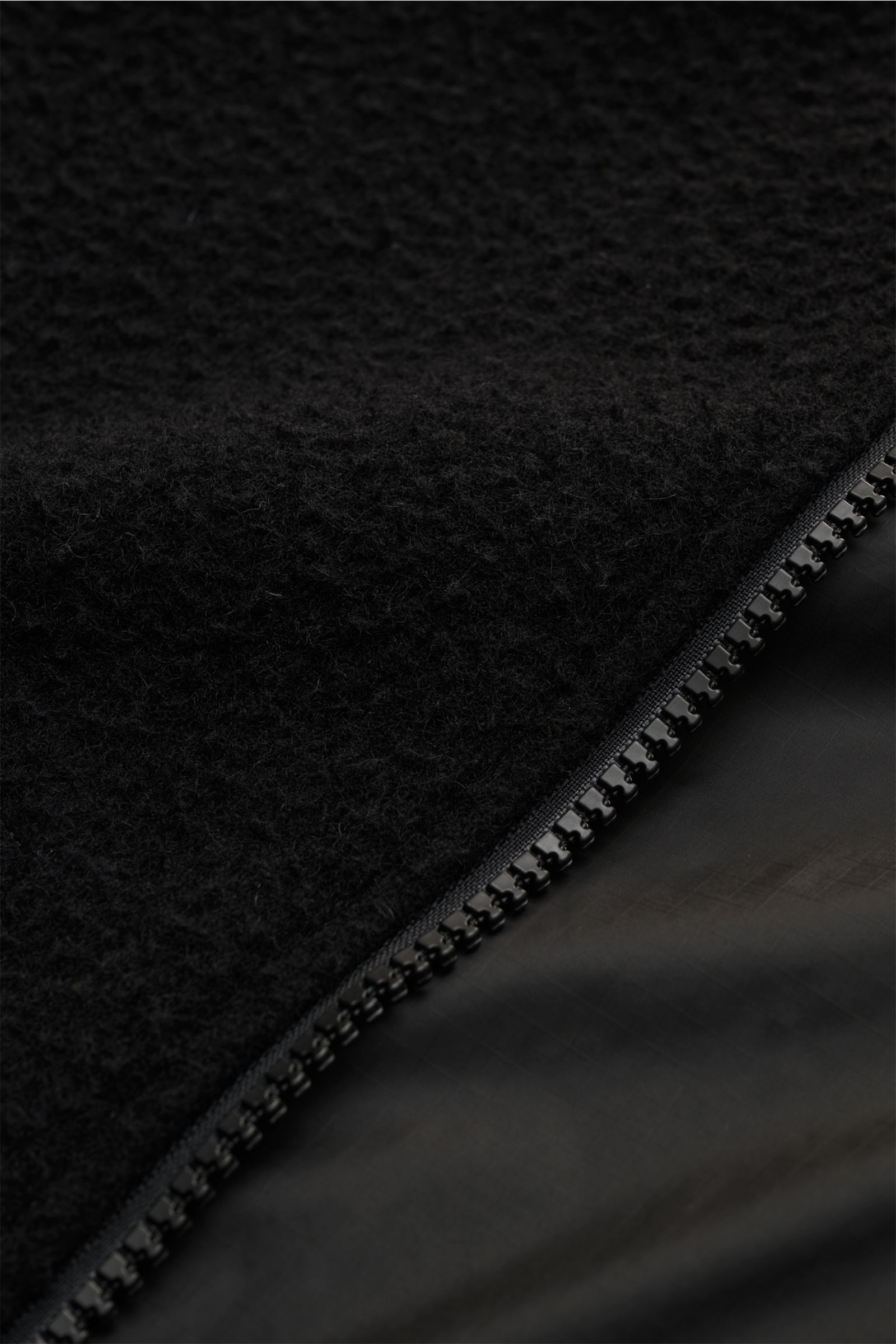 Close-up front detail of Stone Island Blouson 'Panno Ratinato' schwarz showing textured wool-mix fabric and water-repellent smooth zipper area from a diagonal perspective.