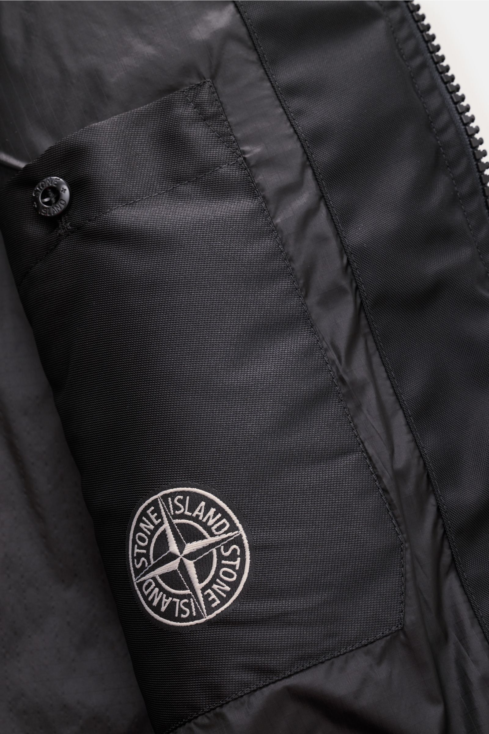 Nahaufnahme der Innenseite der Stone Island Jacke 'Panno Ratinato' navy, zeigt funktionale Brusttasche mit Logo aus Wolle-Microfaser-Mix.