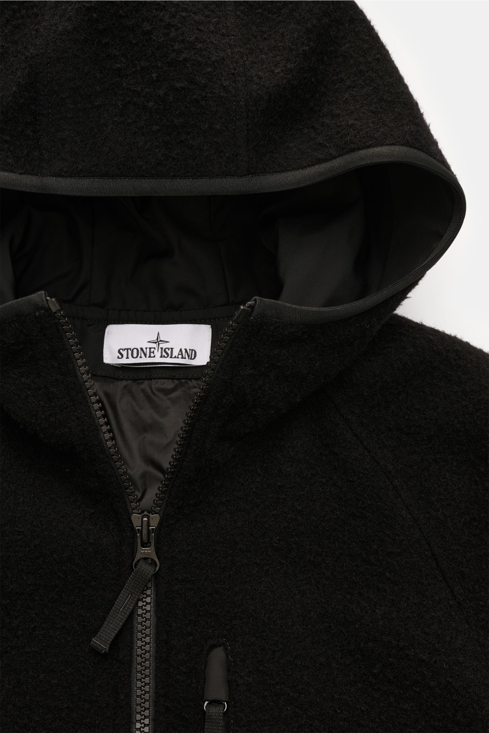 Close-up from above of the Stone Island Jacket 'Panno Ratinato' black hood and front zipper, showcasing its ratiné wool blend fabric and robust two-way zip.

Functional and eye-catching: This STONE ISLAND hooded jacket is an eye-catching, sporty piece 