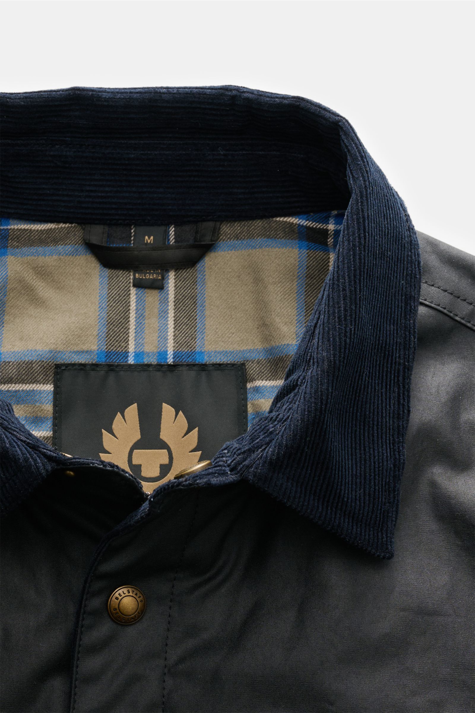 Nahaufnahme der Belstaff Jacke 'Ground' dark olive von oben, gewachste Baumwolle, Slim Fit, Cordbesatz am Umlegekragen, Tartan-Innenfutter.