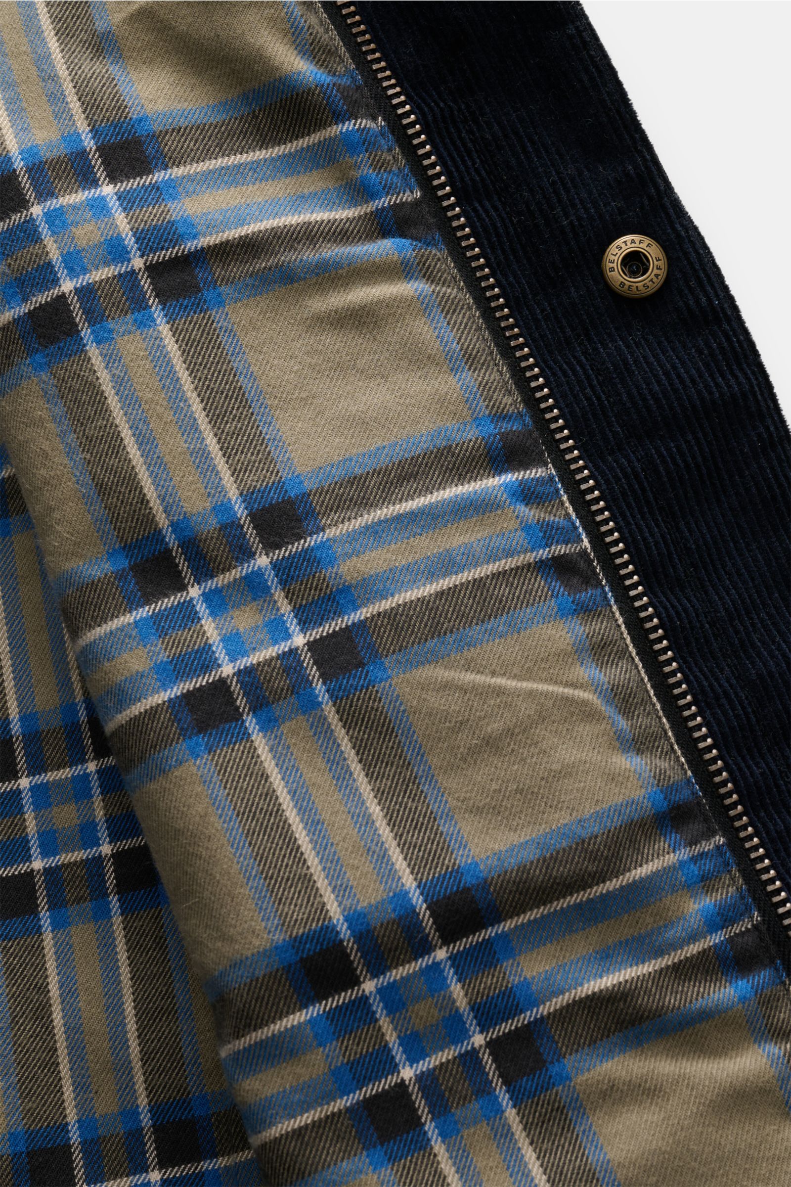 Innenansicht der Belstaff Jacke 'Ground' dark olive mit Tartan-Futter, gewachster Baumwolle und Cordbesatz am Umlegekragen, Nahaufnahme.