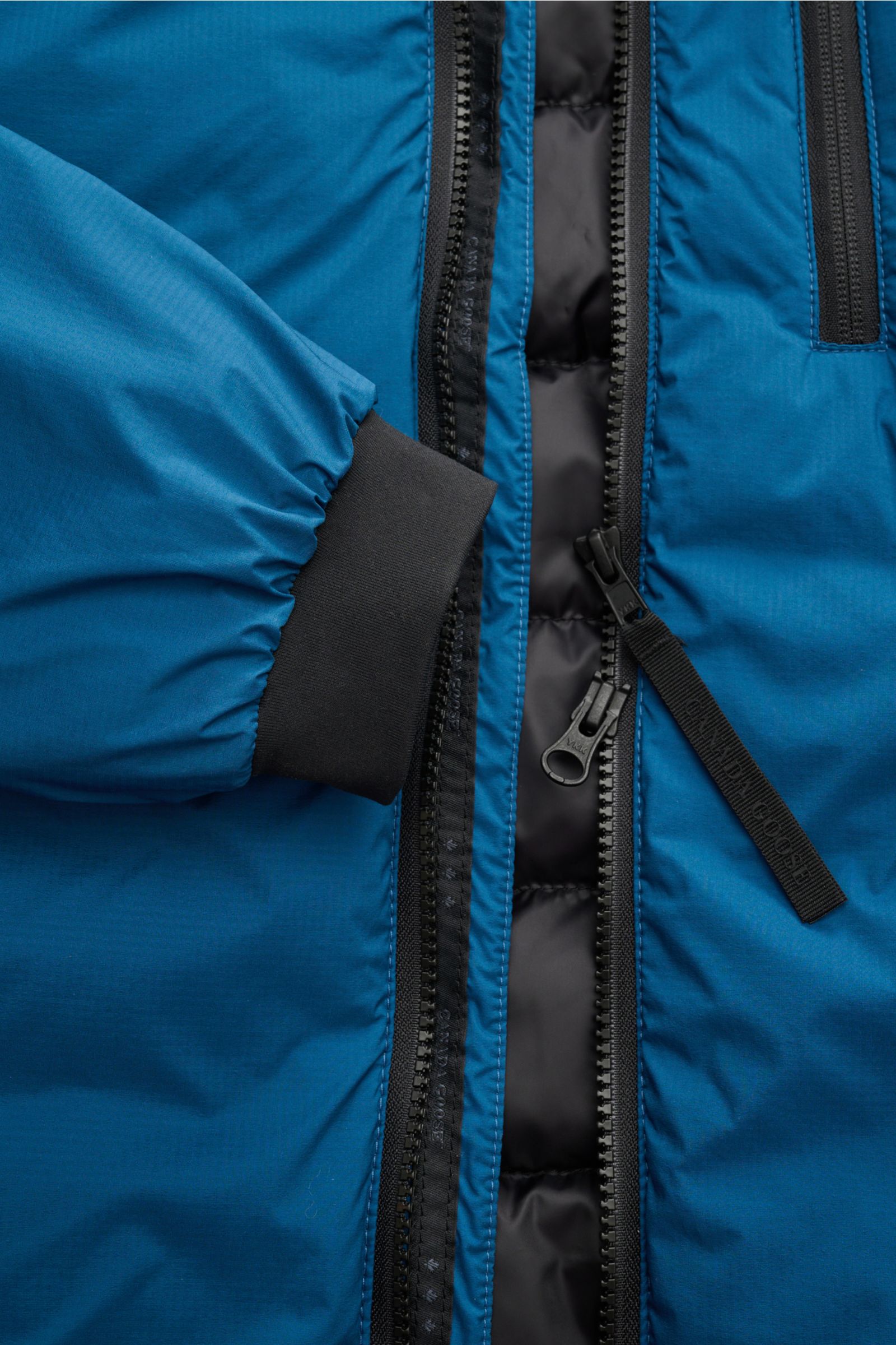 Close-up front view of the Canada Goose Down jacket 'Lodge Hoody' blue, showing ripstop fabric, padded hood, and zipped pockets.
