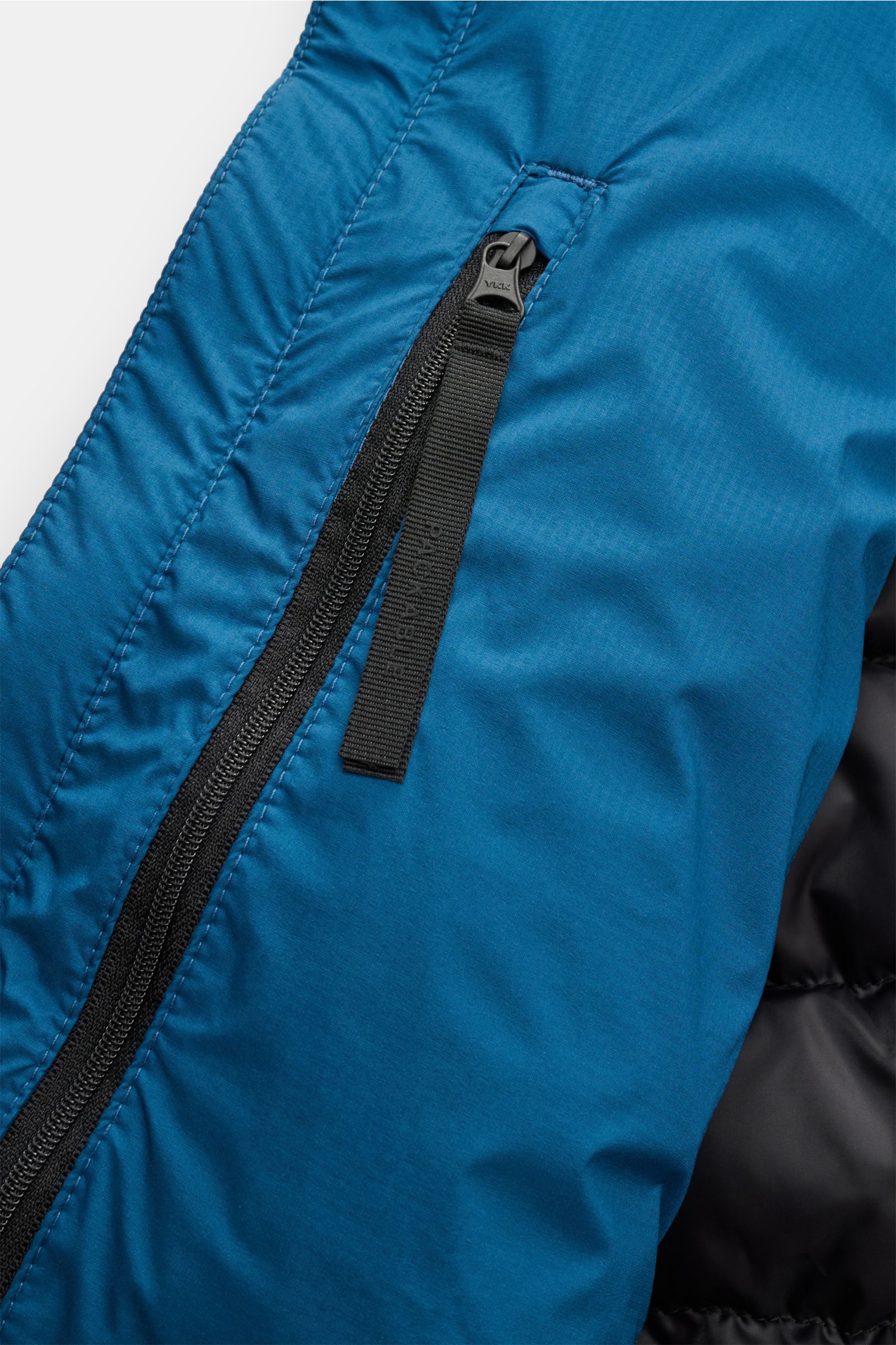 Close-up front detail of the blue Canada Goose Down jacket 'Lodge Hoody' showing the black zip and fabric texture from a top-down perspective.