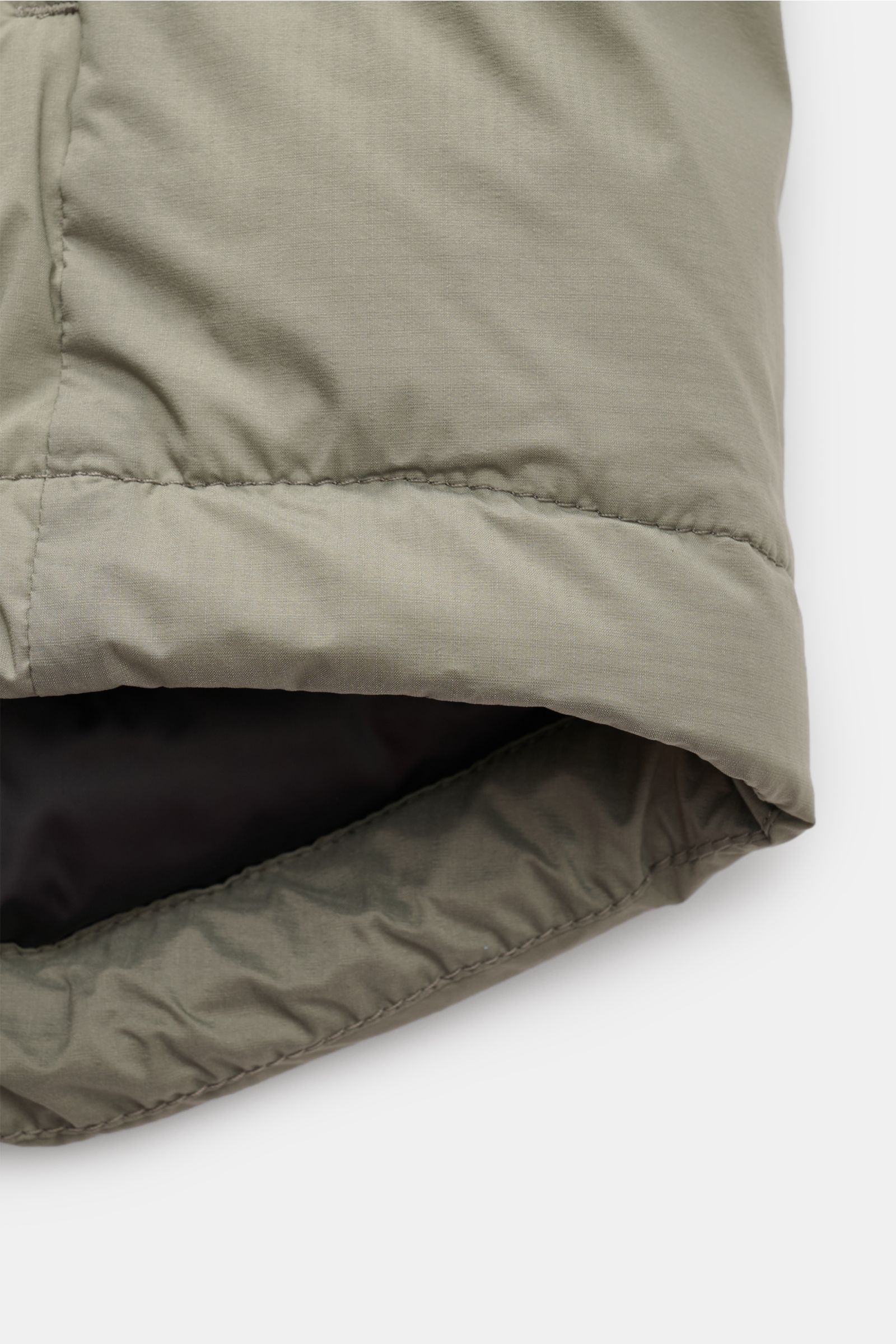 Nahaufnahme der Canada Goose Daunenjacke 'Lodge Hoody' graugrün von unten, zeigt das Ripstop-Microfasergewebe und die wattierte, verstaubare Kapuze.