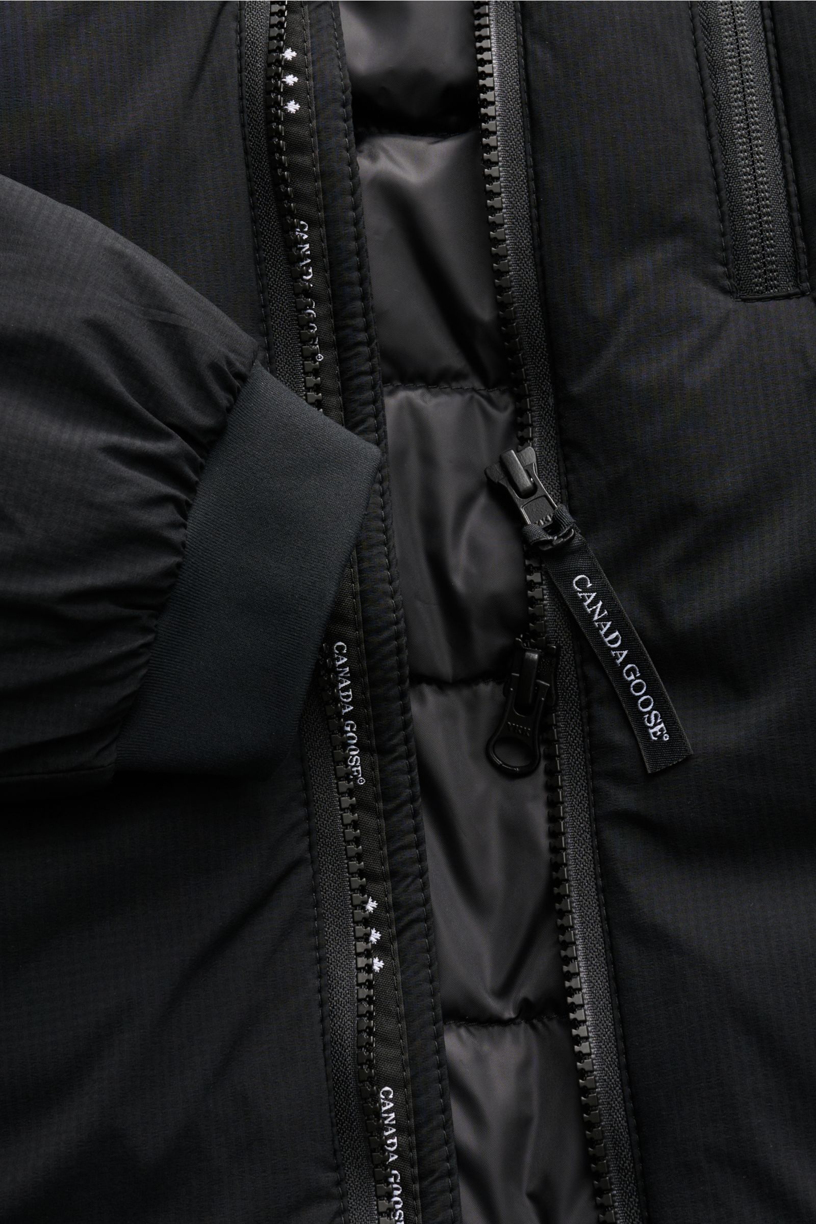 Canada Goose Daunenjacke 'Lodge Hoody' schwarz, Nahaufnahme des Reißverschlusses und Ärmelbündchens, leichte, wattierte Daunenfüllung, Ripstop-Microfaser, Slim Fit, verstaubar.