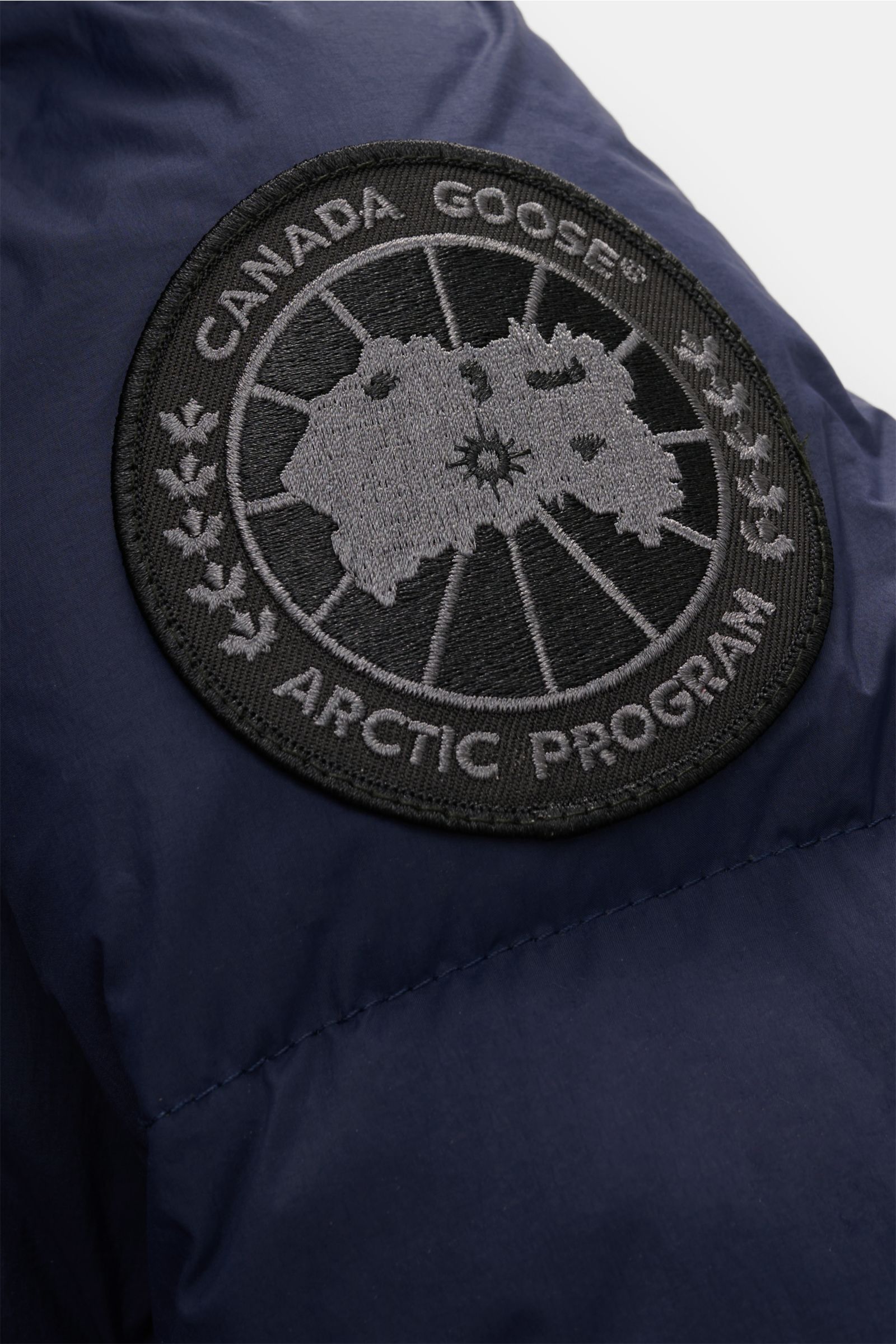 Nahaufnahme des tonalen Canada Goose Logos auf der Ärmelpartie der navy Canada Goose Daunenjacke 'Crofton Puffer' aus Microfaser mit voluminöser Daunenfüllung.