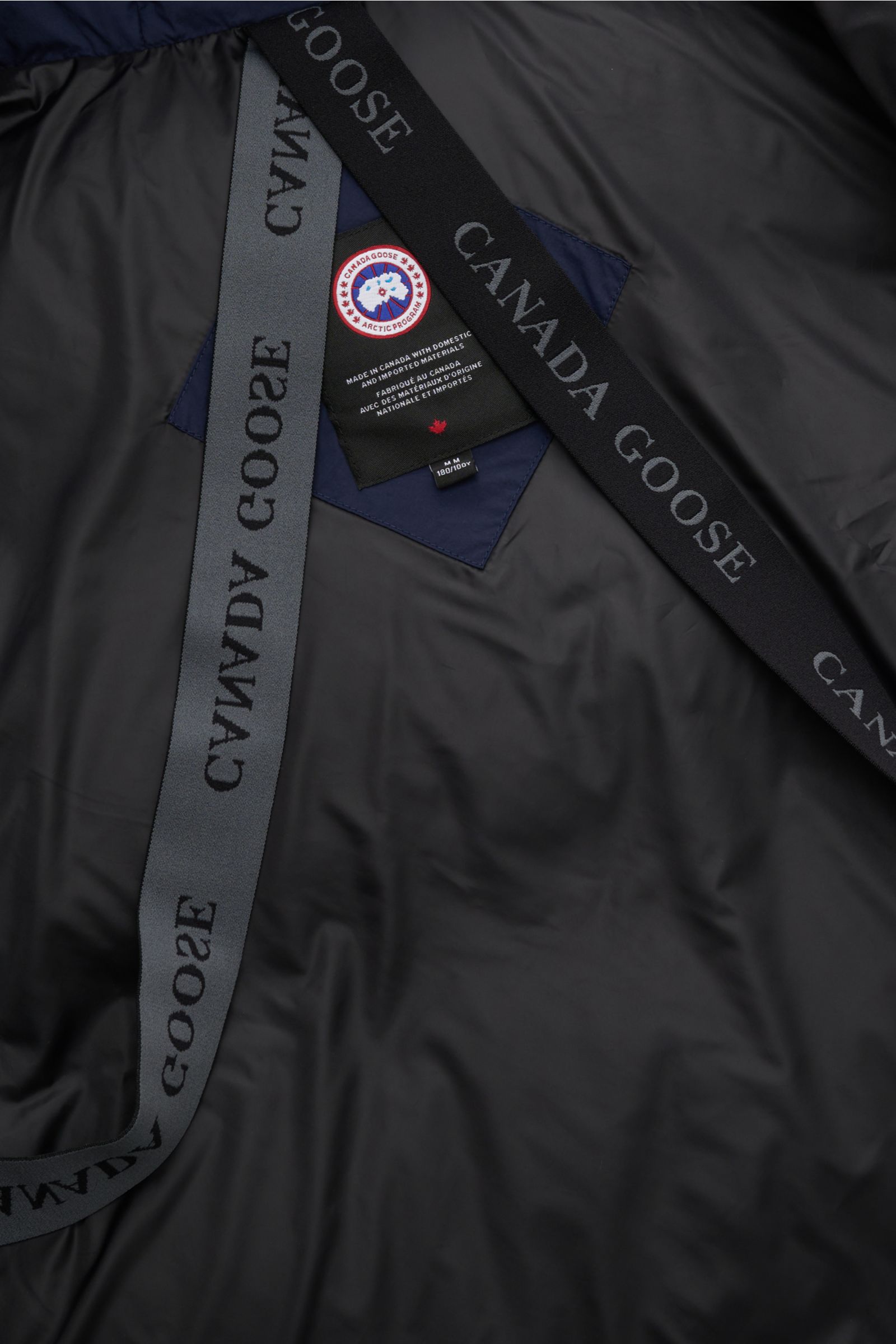 Innenansicht der Canada Goose Daunenjacke 'Crofton Puffer' navy mit glattem Futter, abnehmbaren Rucksackträgern und Markenlabel im Detail.