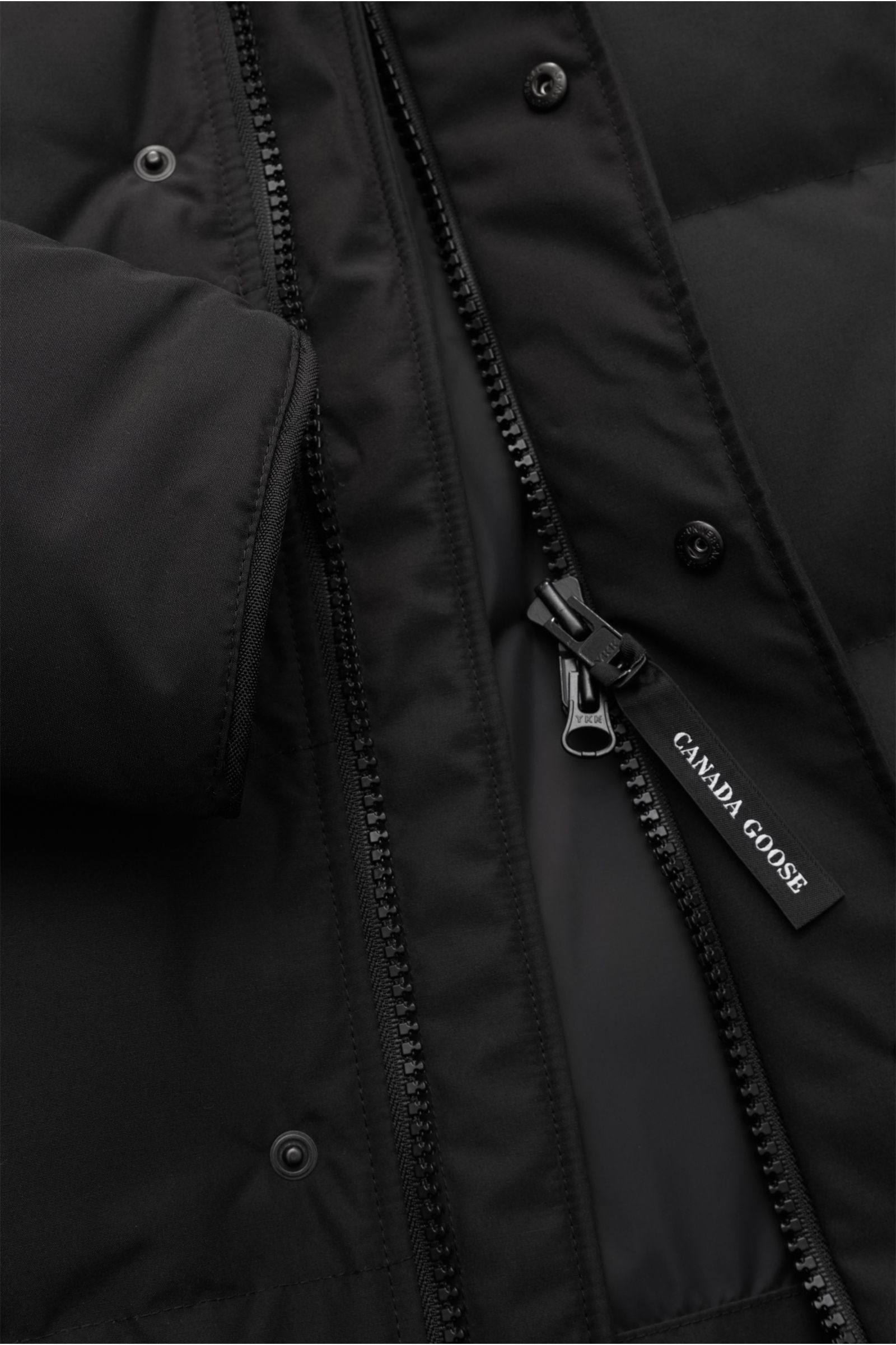 Canada Goose Daunenjacke 'Macmillan' schwarz, Nahaufnahme des robusten Zwei-Wege-Reißverschlusses mit Canada Goose Label, Slim Fit, wasserabweisend.