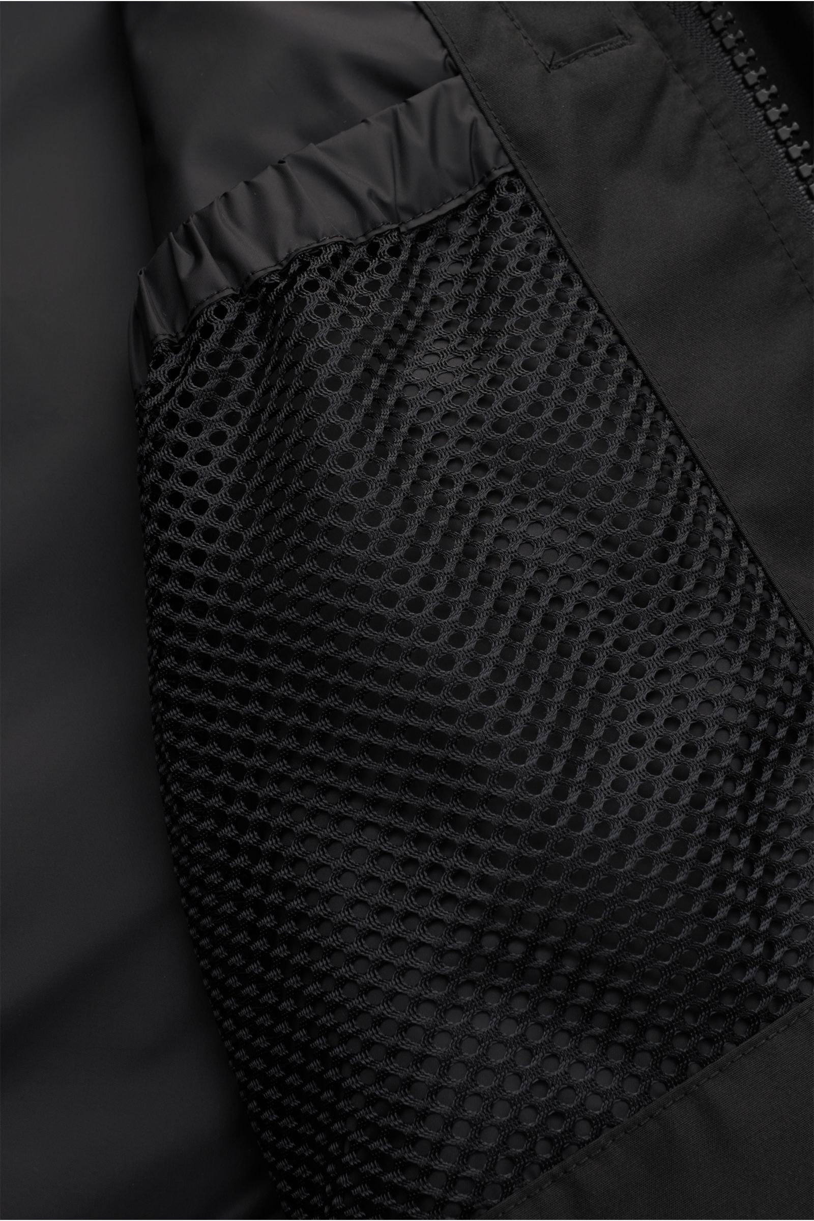 Nahaufnahme des Innenfutters der Canada Goose Daunenjacke 'Macmillan' schwarz mit Mesh-Innentasche und elastischem Bund aus Microfaser-Baumwoll-Mix.